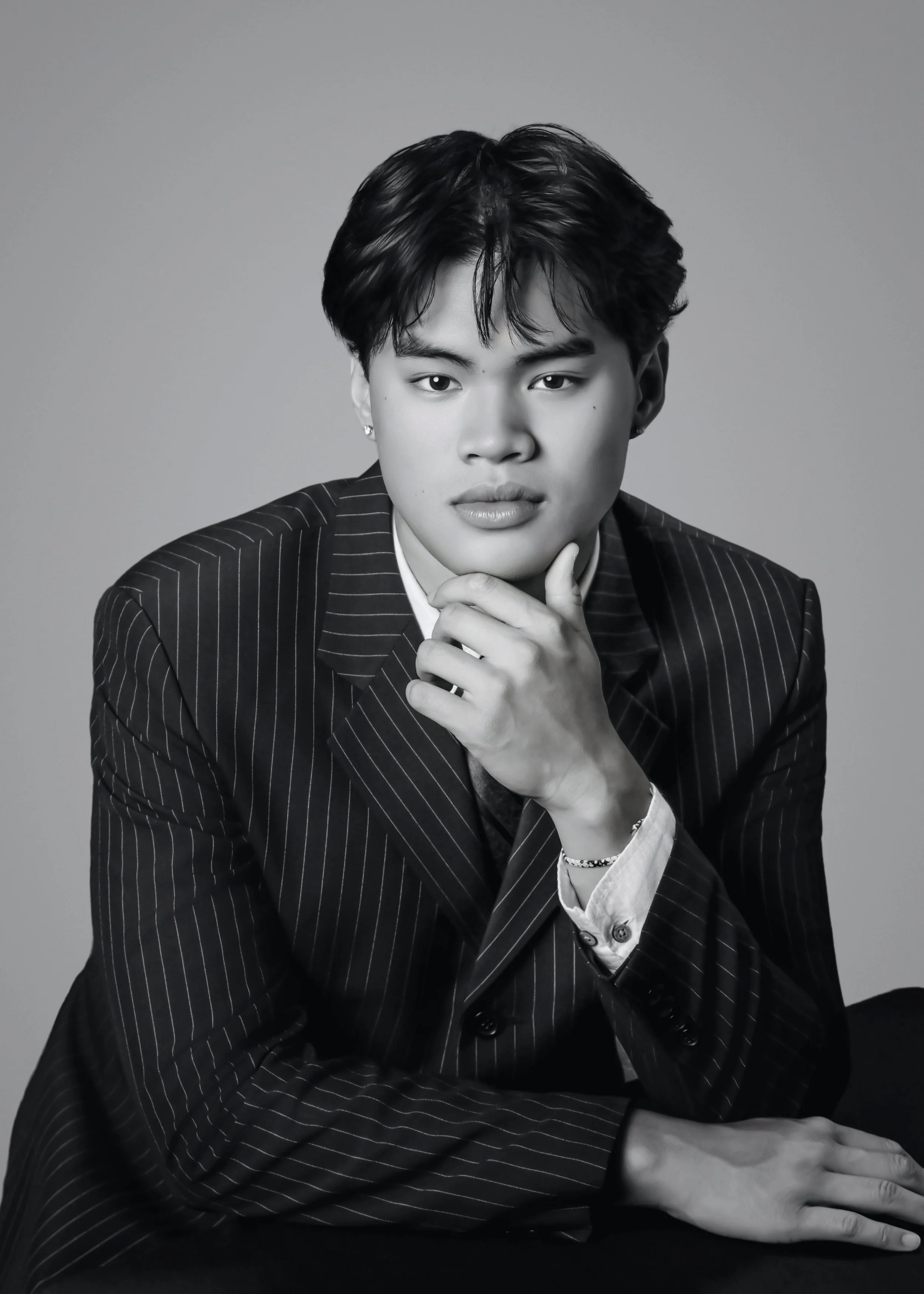 polished black and white photo of senior boy wearing tuxedo, looking thoughtful and relaxed