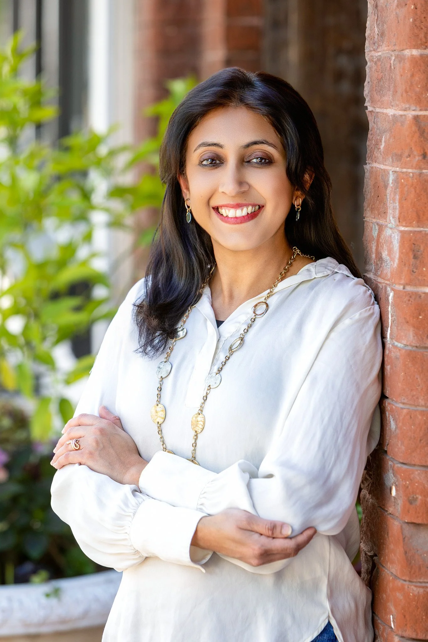 elegant headshot of woman leaning against vintage brick wall.