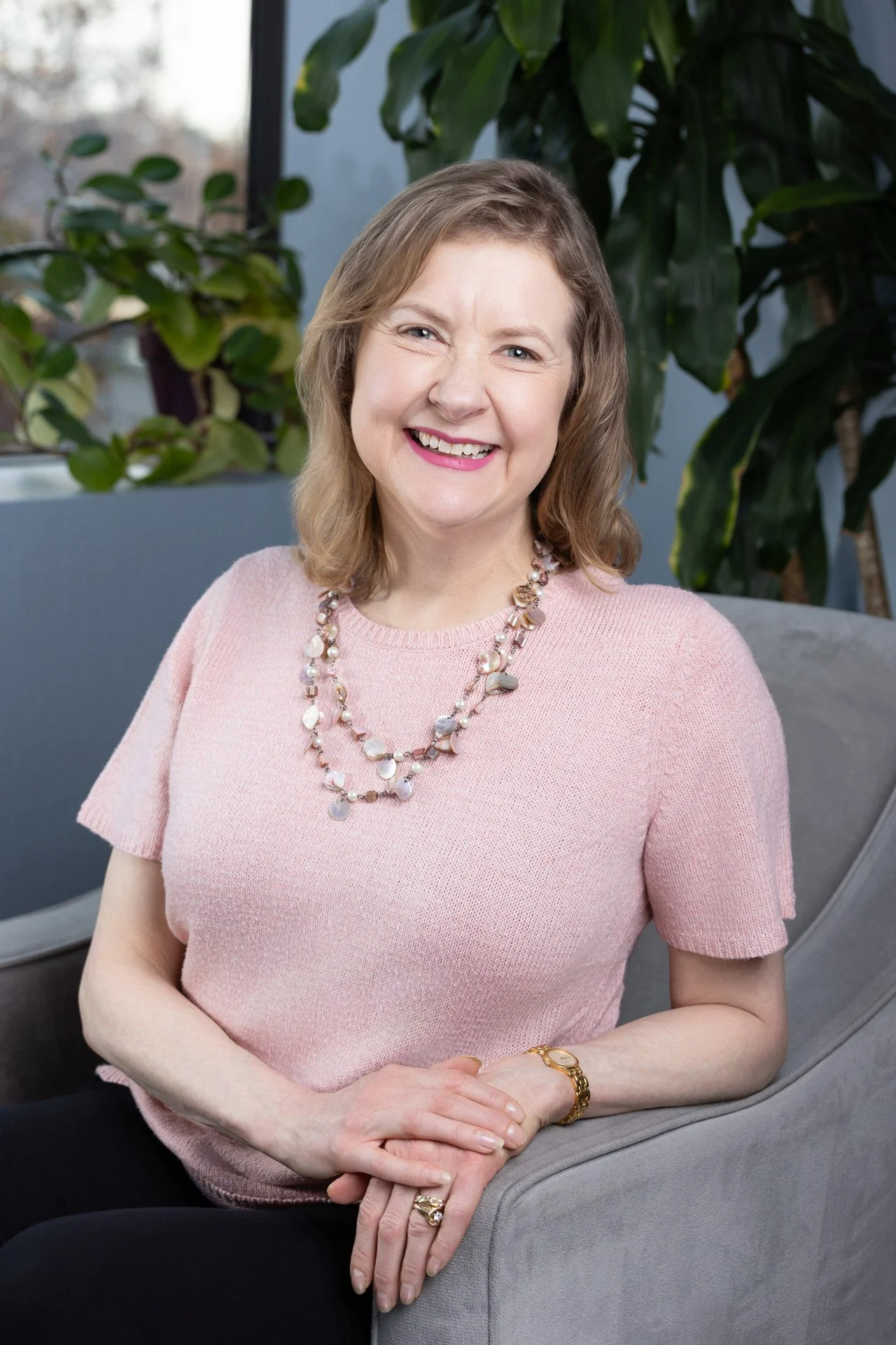 female therapist sitting on chair by a window in office setting. 