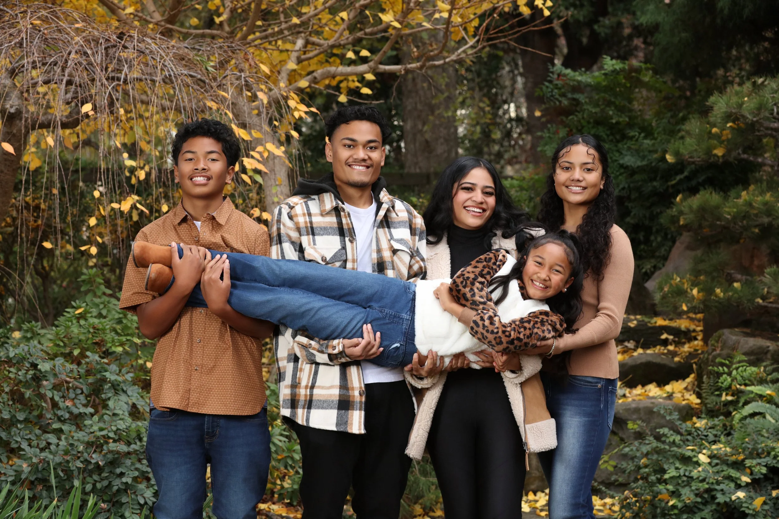 four teenagers holding sibling outdoor garden