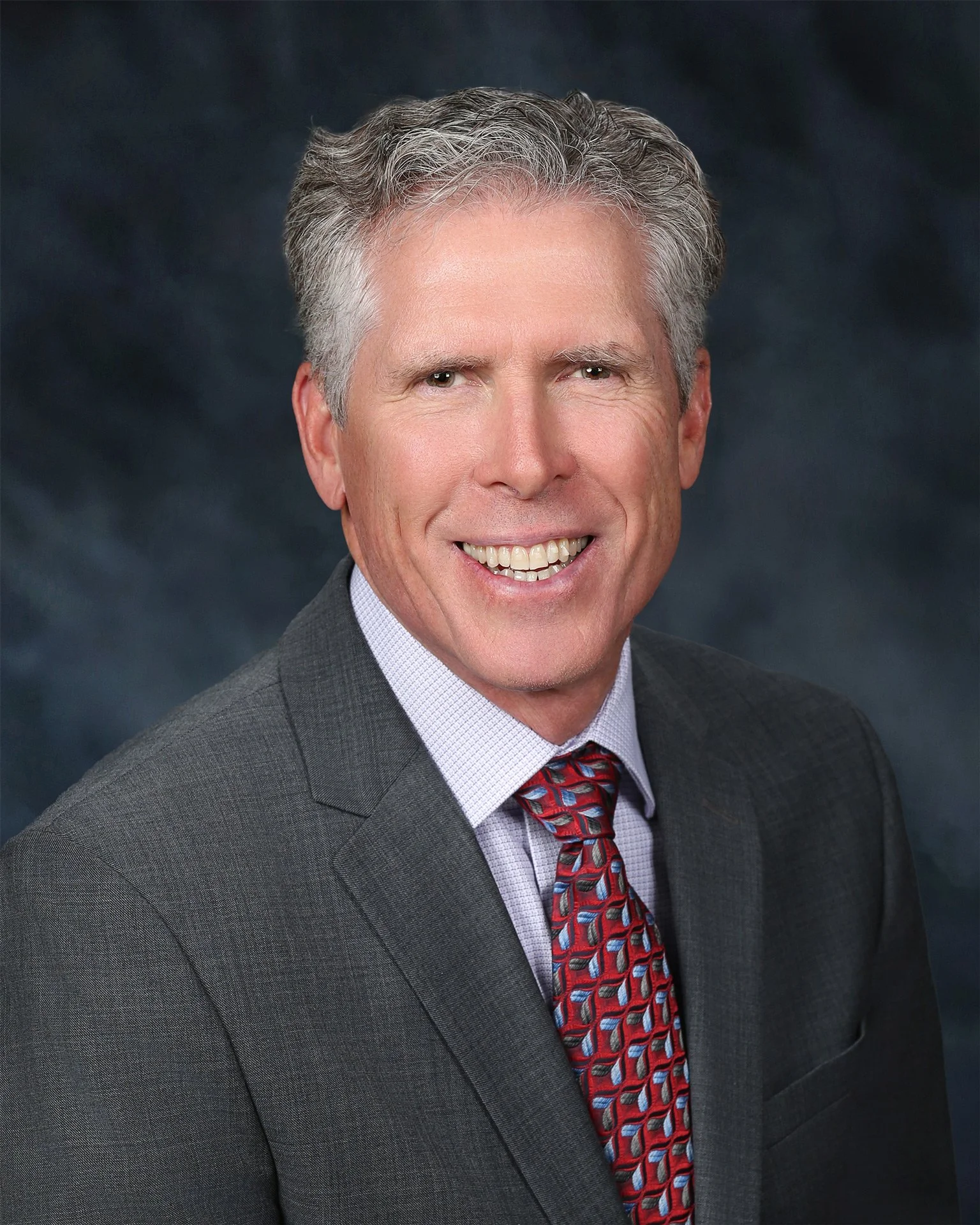 Male attorney professional headshot on dark background.
