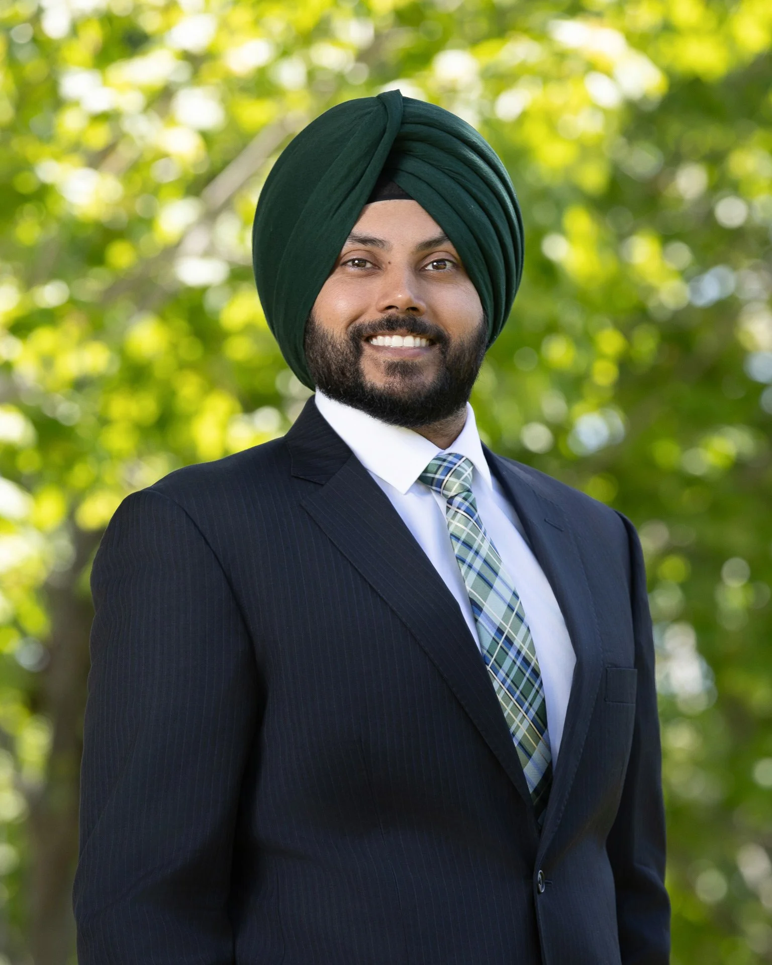 headshot of male professional wearing formal business attire in natural outdoors. 