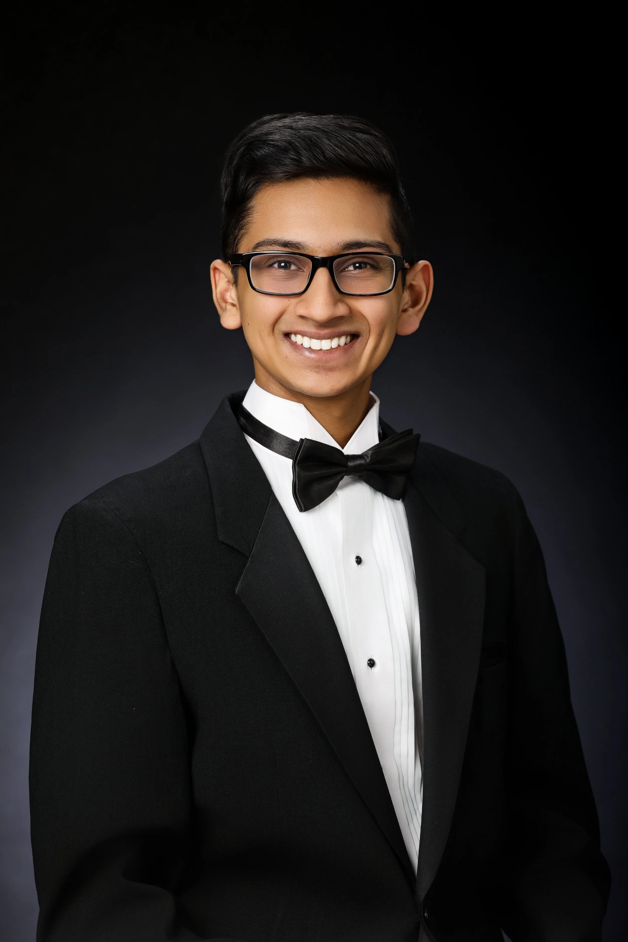 high school senior boy wearing a classic black tux with bowtie for yearbook look