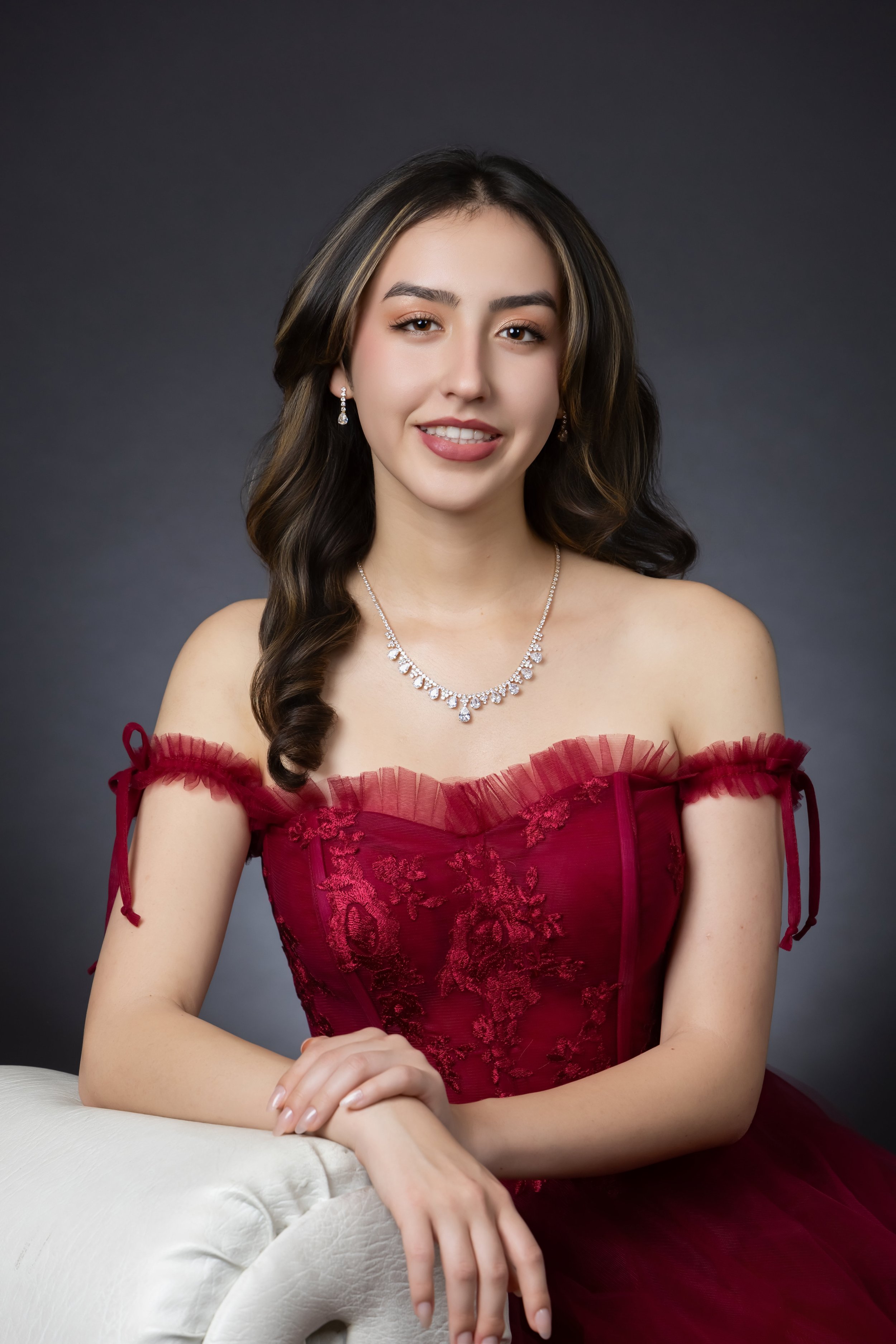 high school senior girl wearing formal dress sitting comfortably on sofa in studio