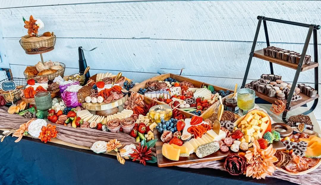 A lavish dessert and cheese platter with various cheeses, fruits, chocolates, and pastries arranged on a decorative table.