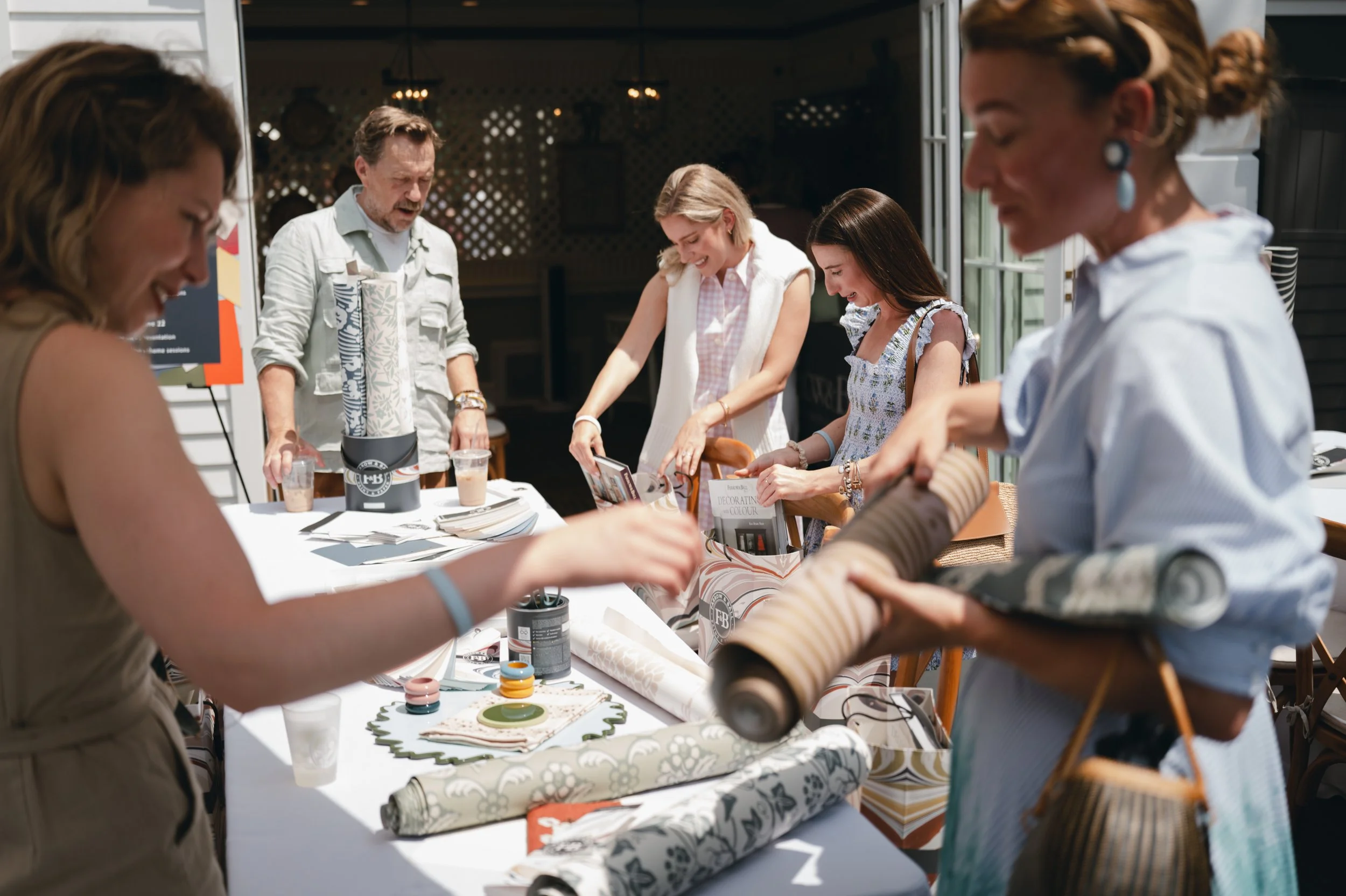 People gathered around a table engaged in arts and crafts activities outdoors, with various craft supplies on the table.
