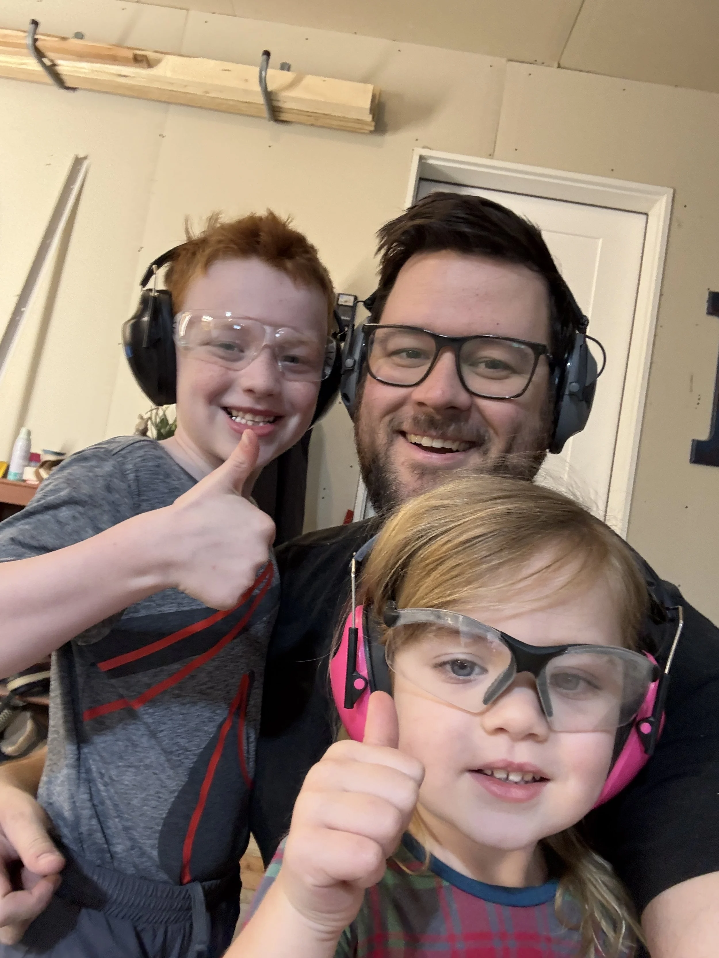 The owner with his wearing safety glasses and earmuffs taking a selfie in a workshop.