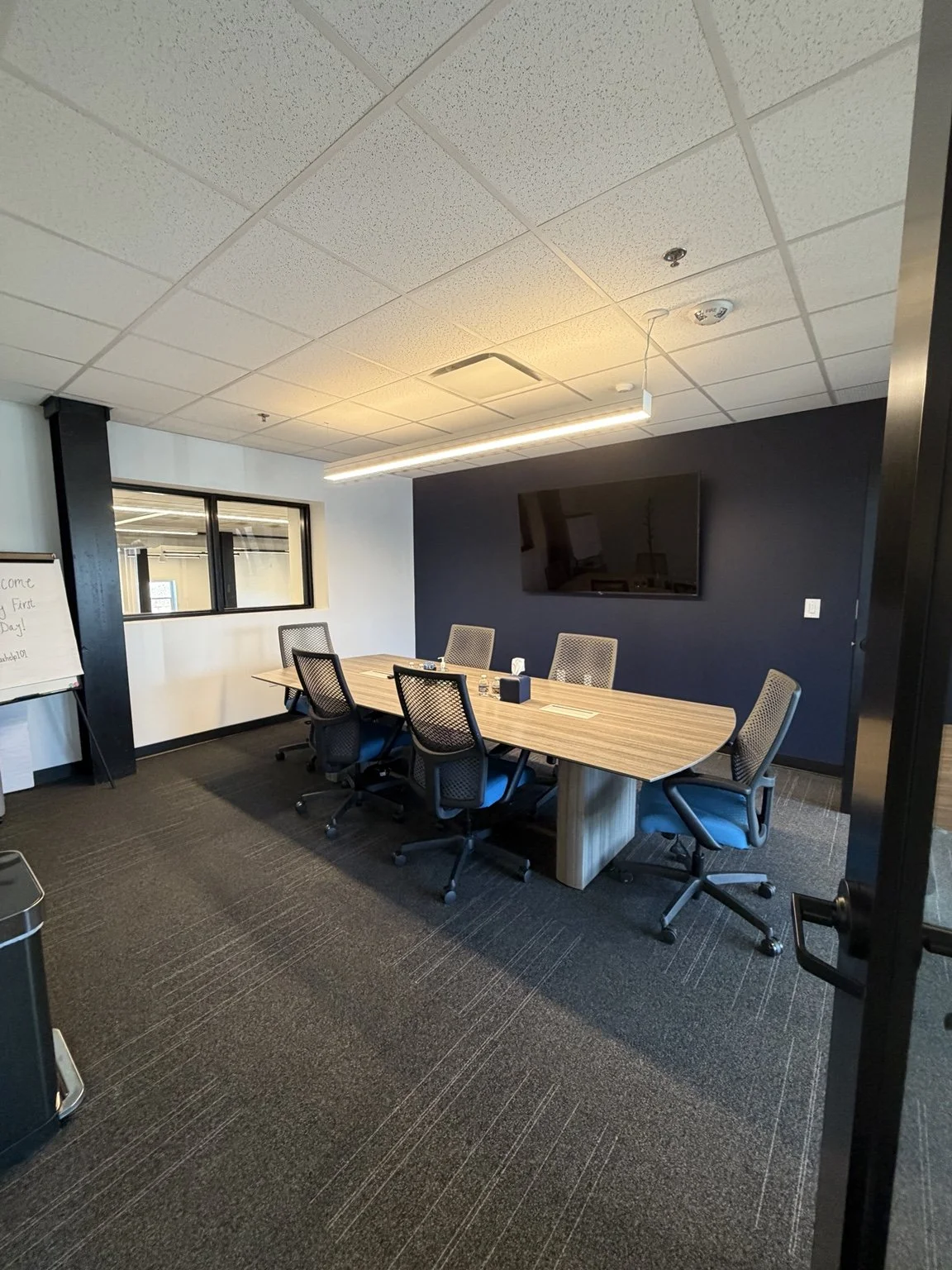 photo shows a small conference room with blue and white contrast detailing -- a table of six modern chairs is shown