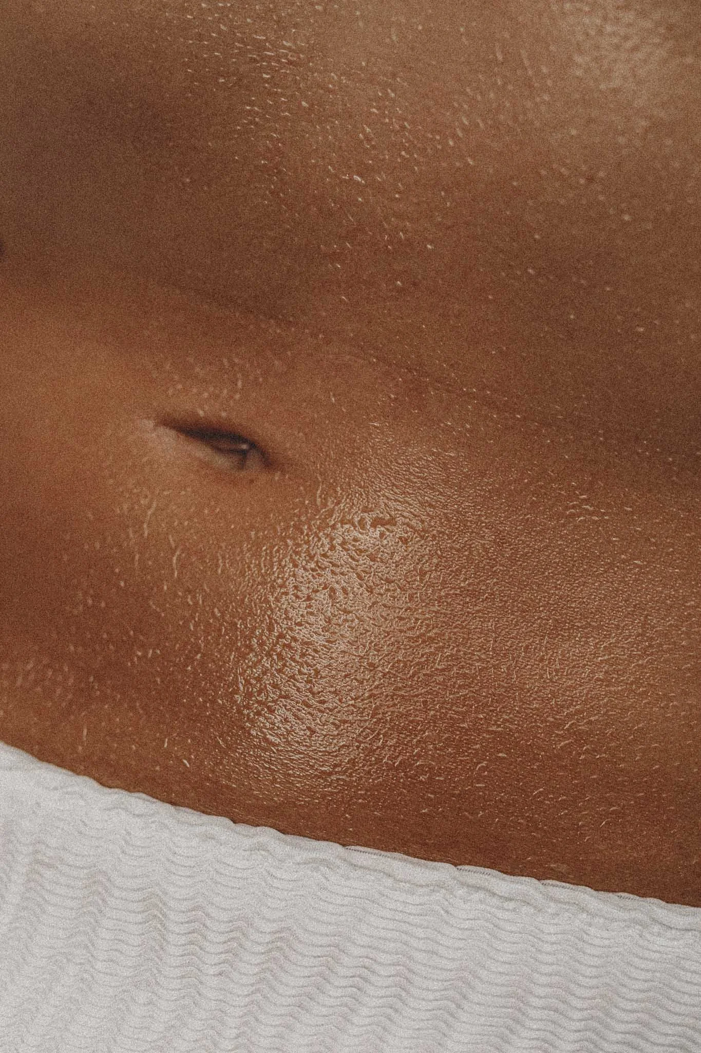 Close-up of a person's face with dark skin, showing facial features and a textured white fabric at the bottom.