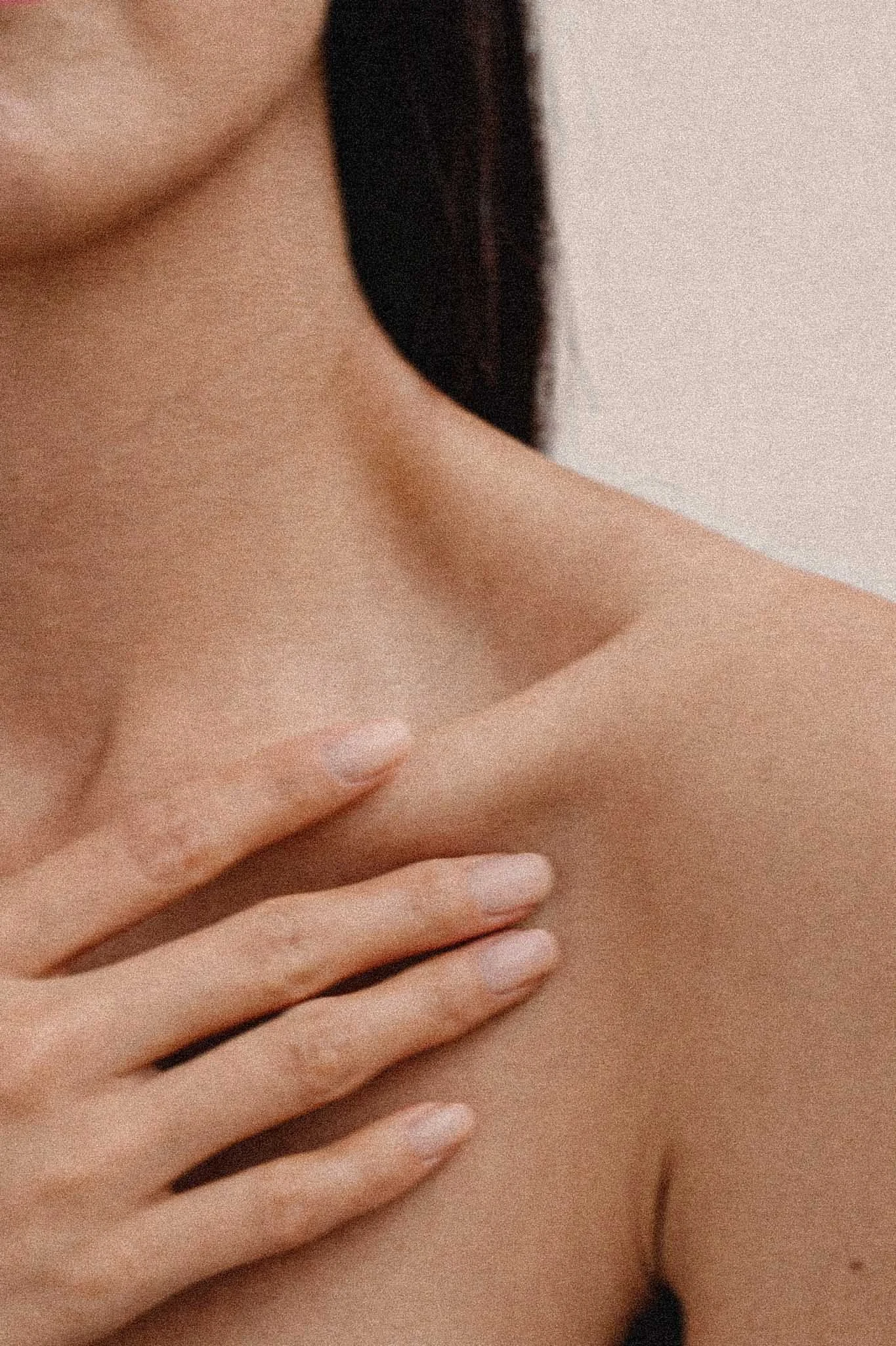 A close-up photo of a person's hand placed on their chest, showing smooth skin, from the neck to the hand.