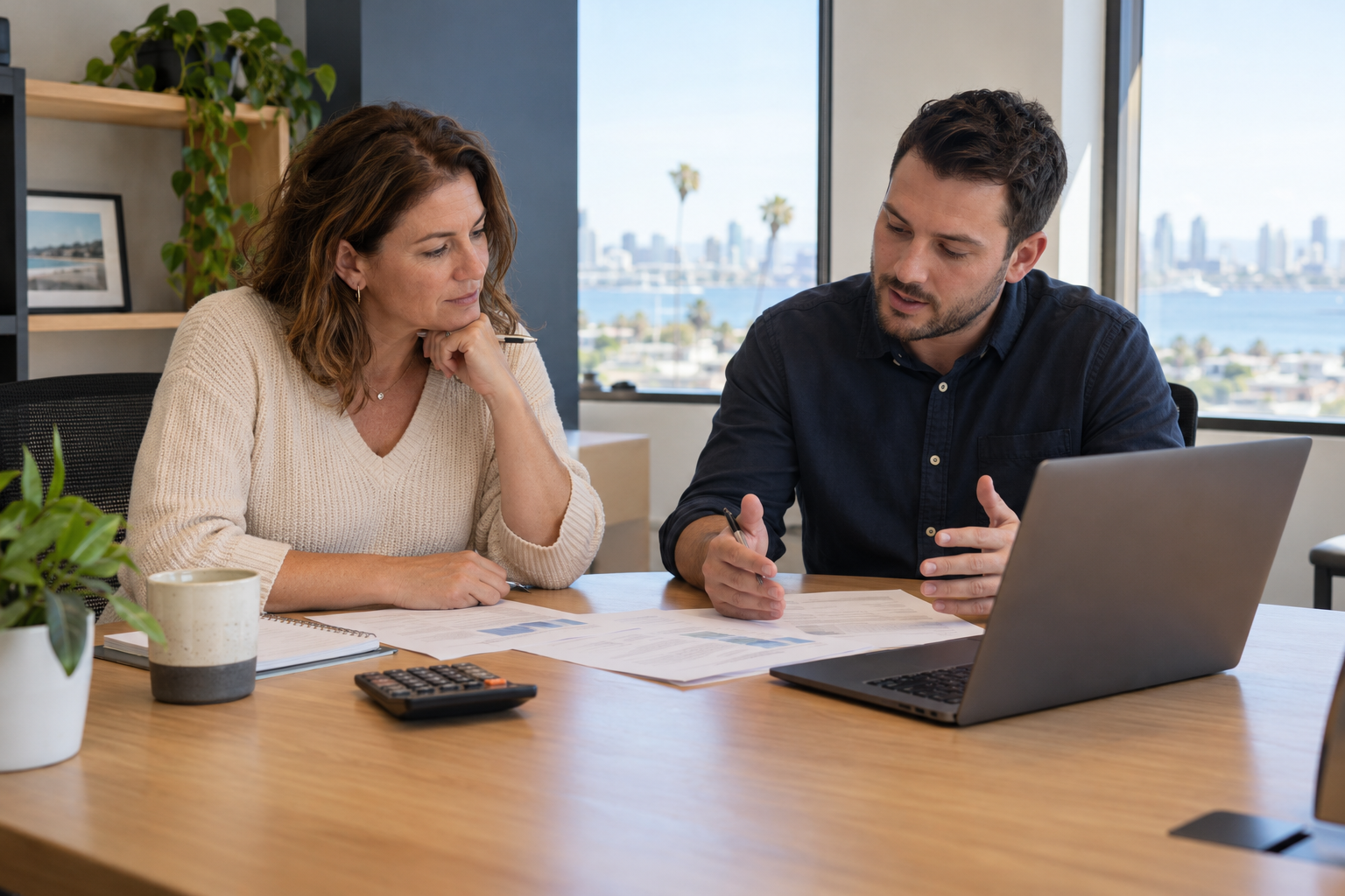 Business owner and IT adviser reviewing a budget beside a laptop.
