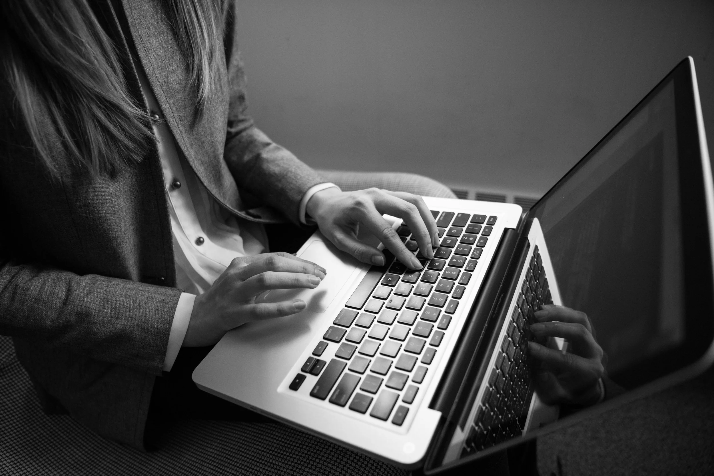 Two people, one in a suit and the other in a blazer, working together on a laptop.