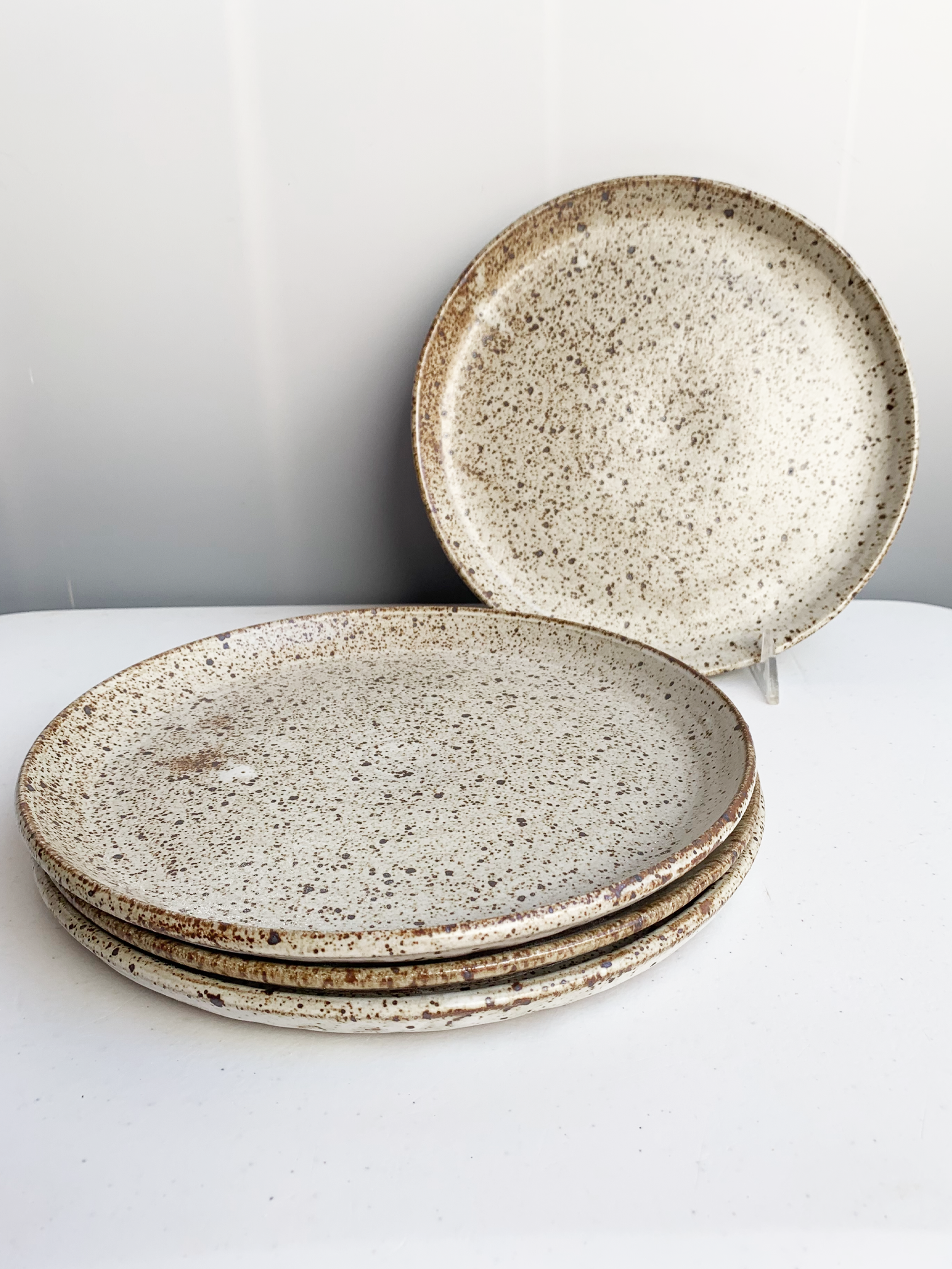 Handmade stoneware dinner plate with a soft gray speckled glaze and warm brown flecks.