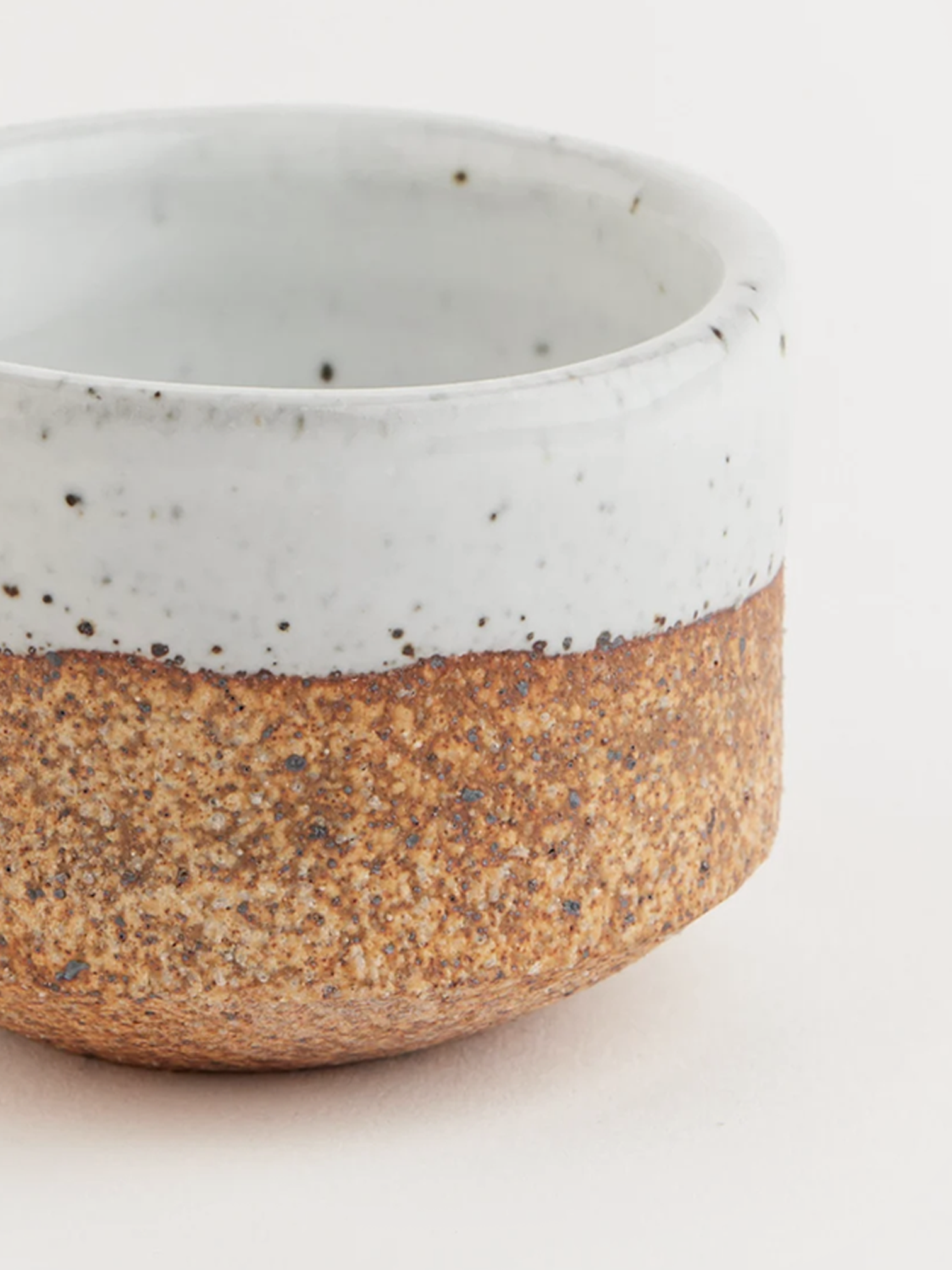 Handmade stoneware match striker with a raw orange-brown clay base, white glazed rim, and green-tipped matches inside.