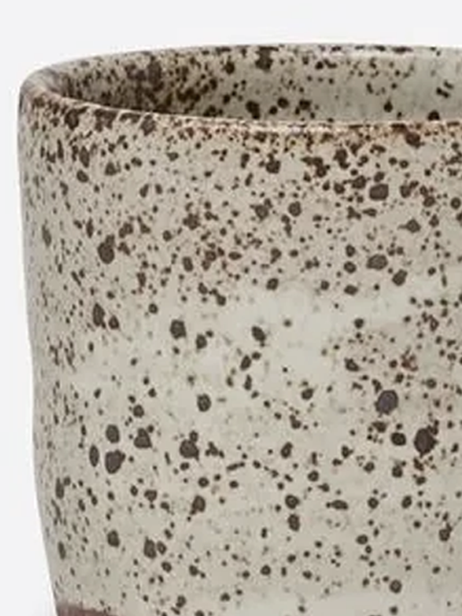 Handmade cylindrical stoneware mug with a pale speckled glaze, exposed brown clay base, and rounded handle.