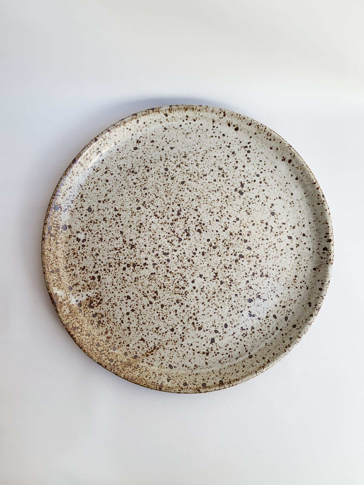 Handmade stoneware dinner plate with a soft gray speckled glaze and warm brown flecks.