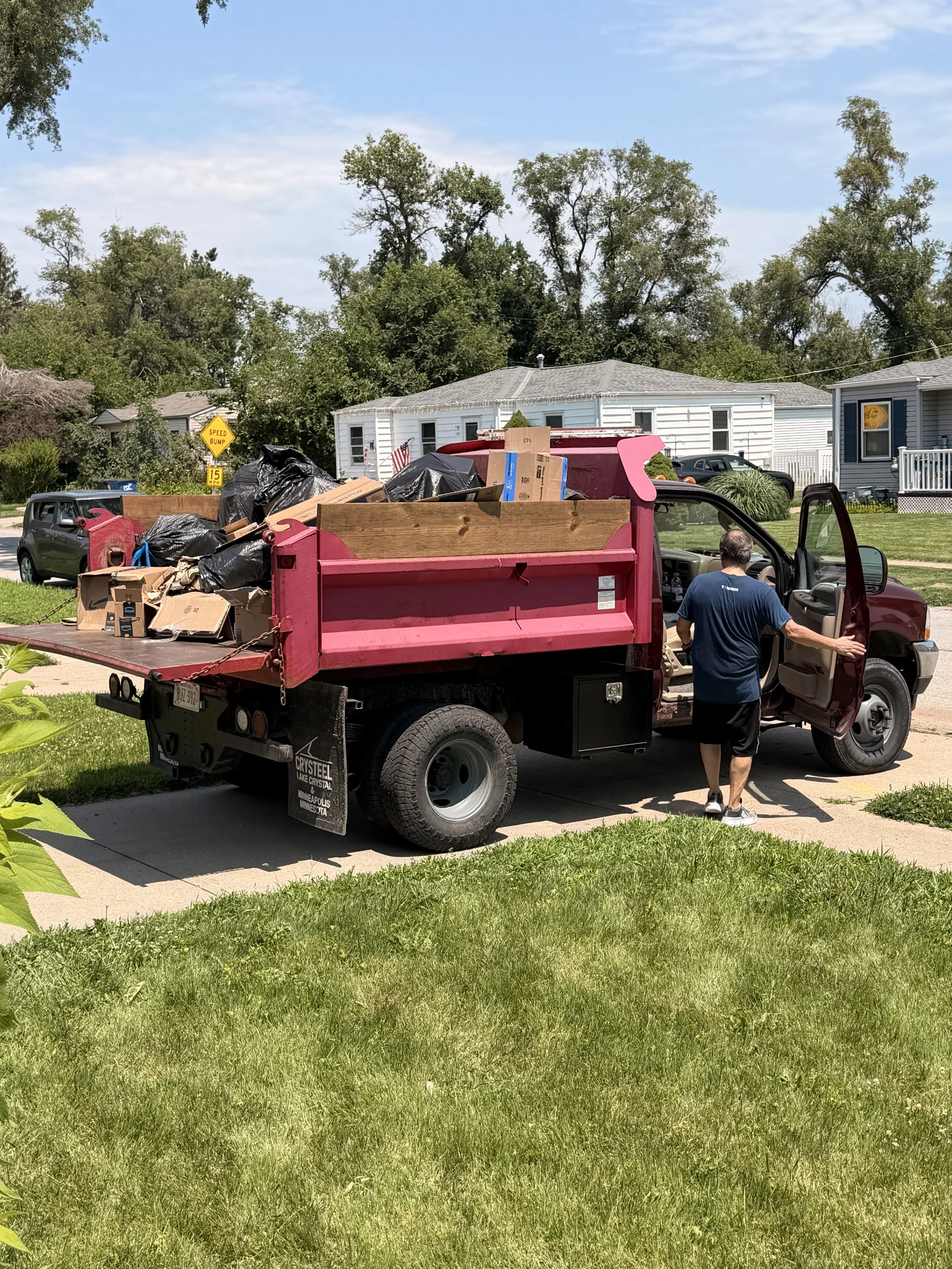 Big Dog Hauling and Junk Removal loading household junk into a dump truck in Bellevue, Nebraska.