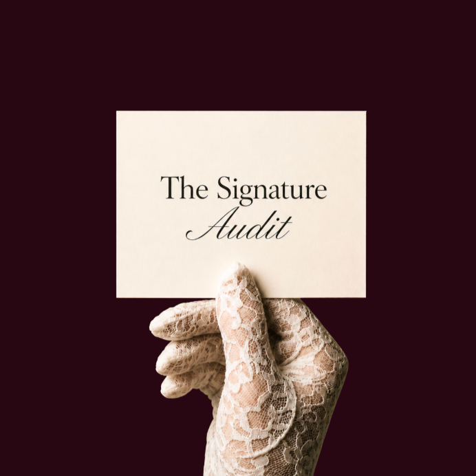 A hand wearing a lace glove holding a Business card with the text "The Signature Audit" against a dark background.