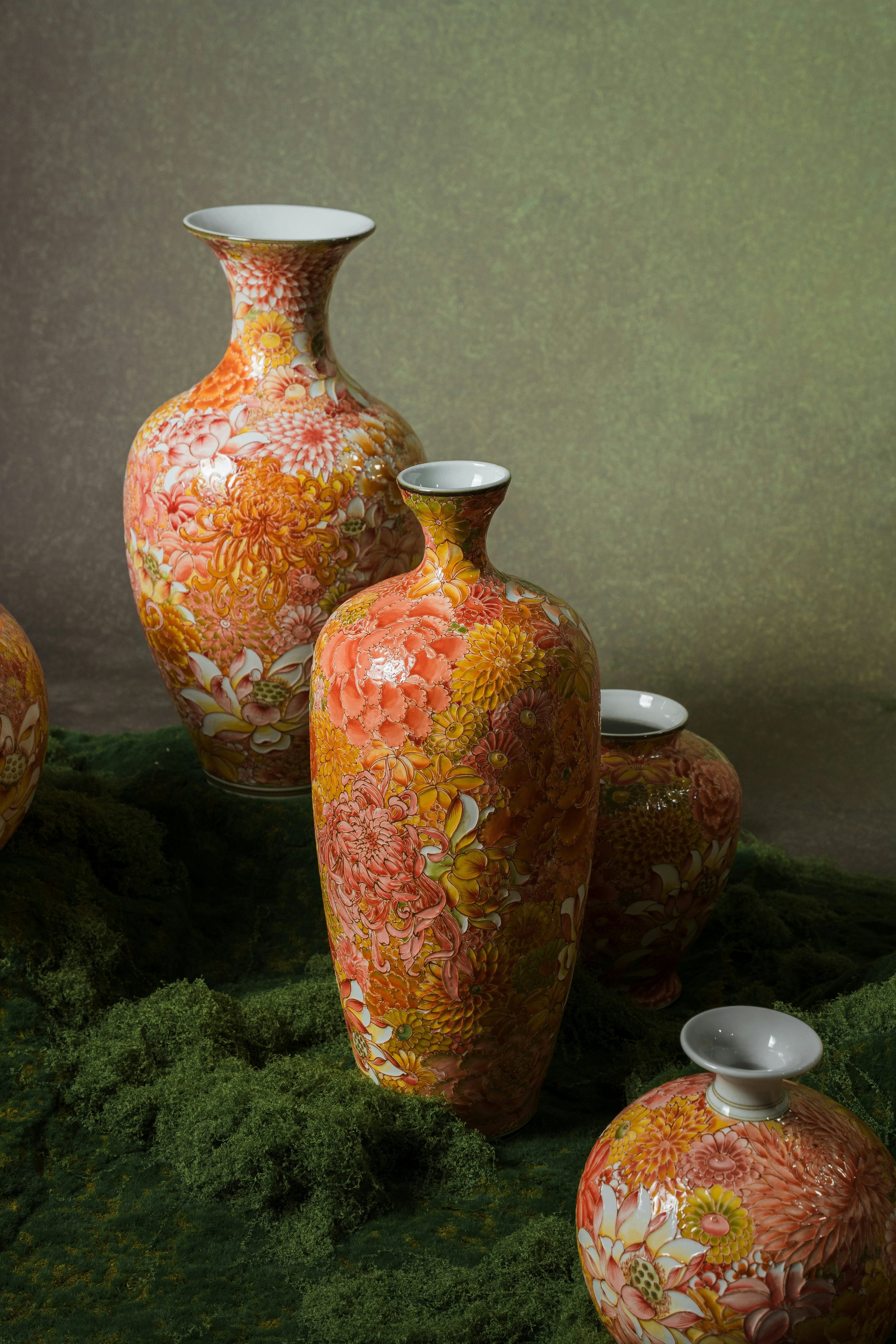 Colorful porcelain vases with floral patterns placed on a landscape with small green bushes.