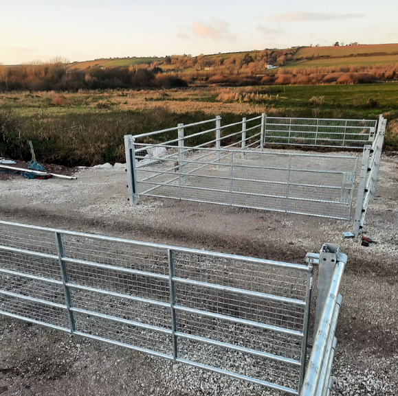 Two metal gates along the Waterford Greenway cycle route in rural area with fields and hills in the background.