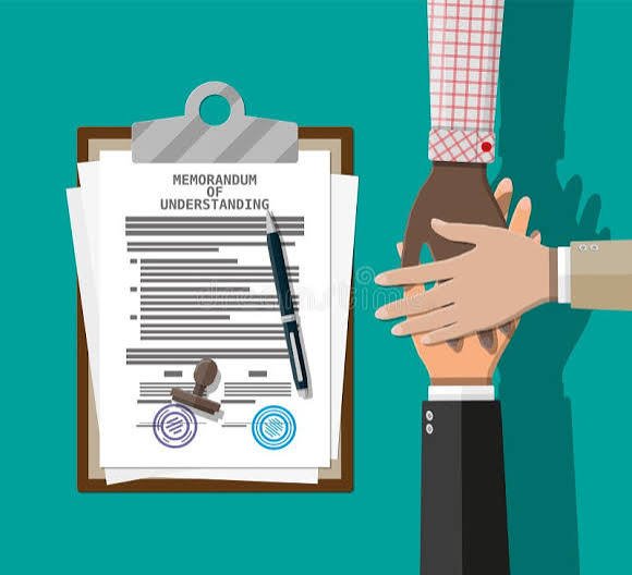 Two people shaking hands near a clipboard with a signed memorandum of understanding.