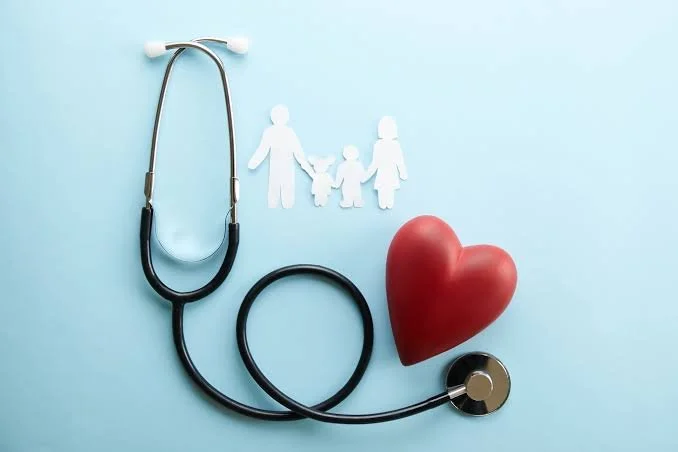 A stethoscope, a red heart, and paper cutouts of a family holding hands on a light blue background.