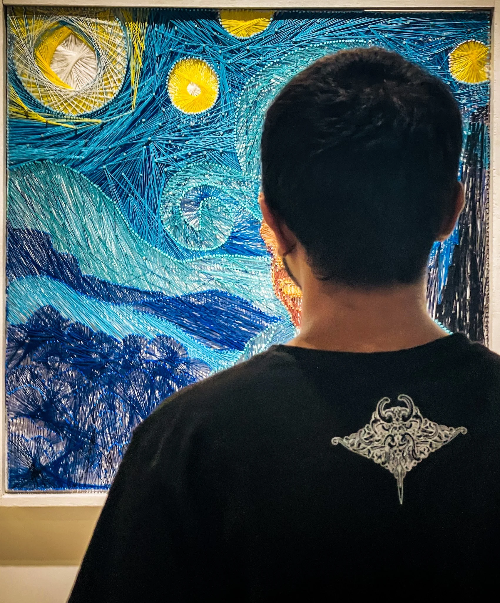 Person viewing a tapestry inspired by Vincent van Gogh's Starry Night, featuring swirling patterns of blue, yellow, and white.
