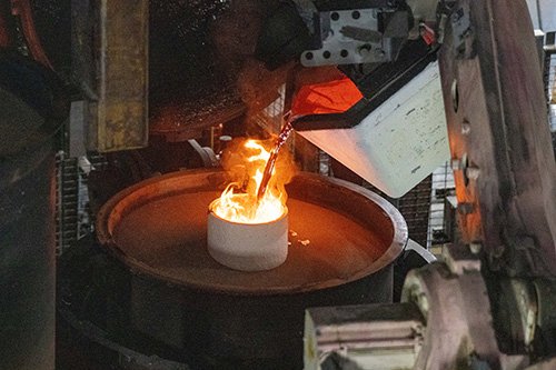 Metalcasting professional pouring molten metal during production.