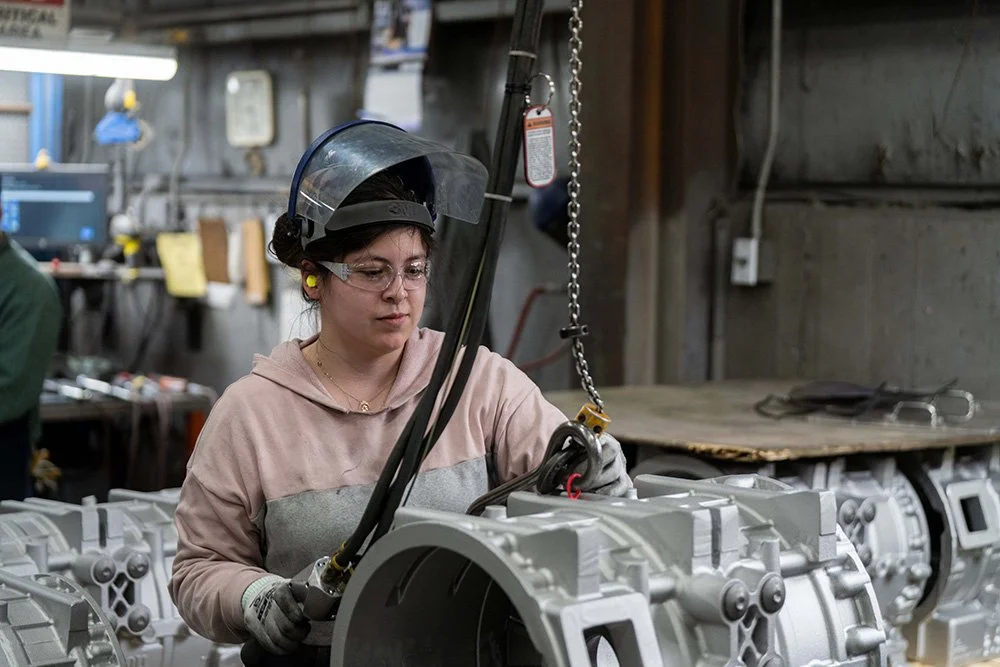 Manufacturing employee operating industrial equipment inside a modern foundry.