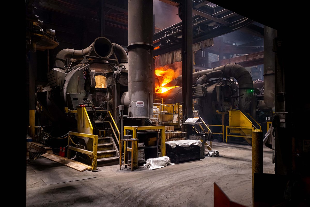 Molten aluminum being poured into molds inside a foundry.