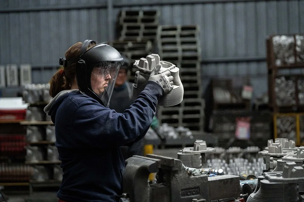 Woman inspecting precision metal cast components in a manufacturing facility