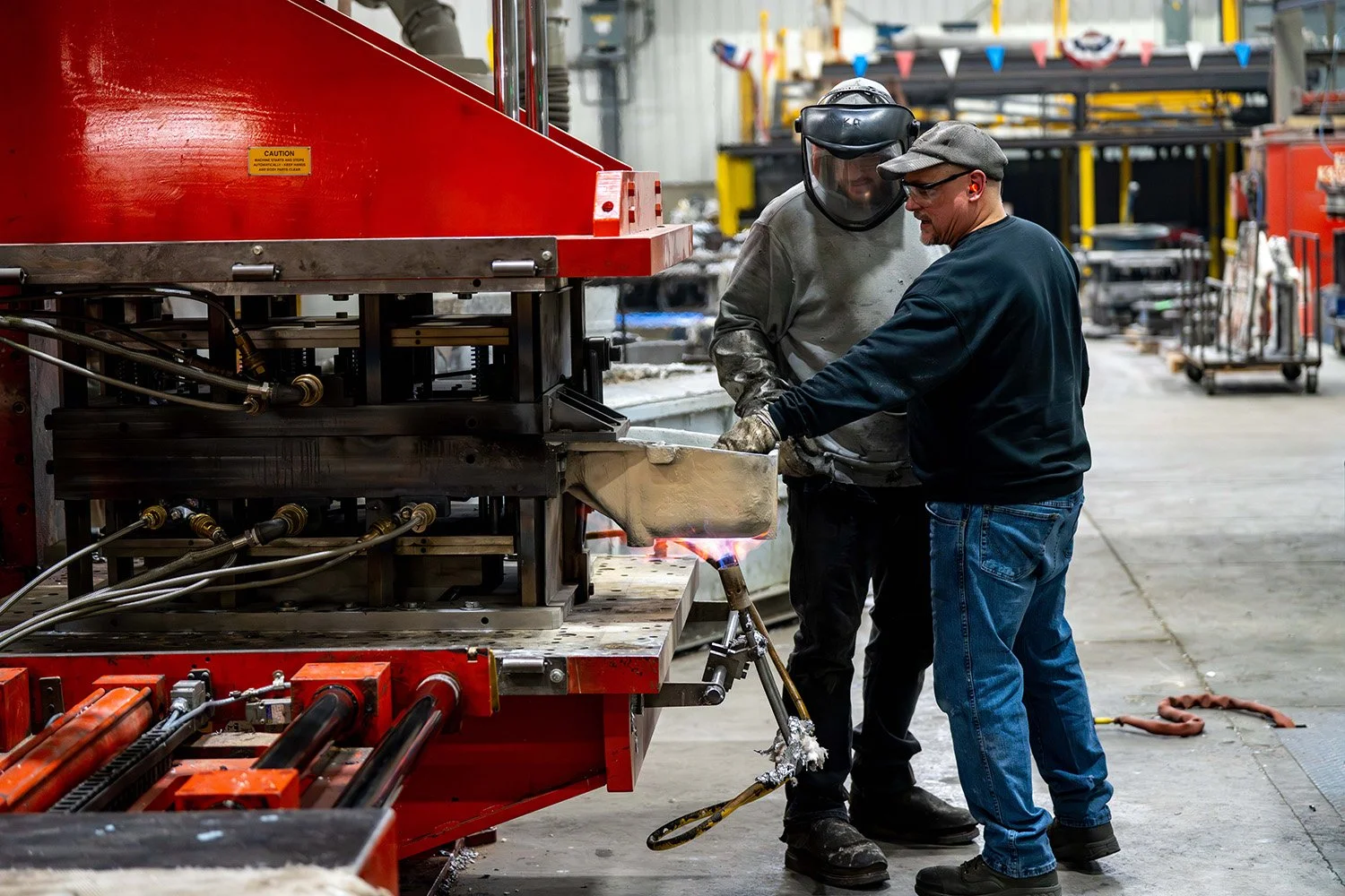 Foundry workers handling molten metal during the casting process.