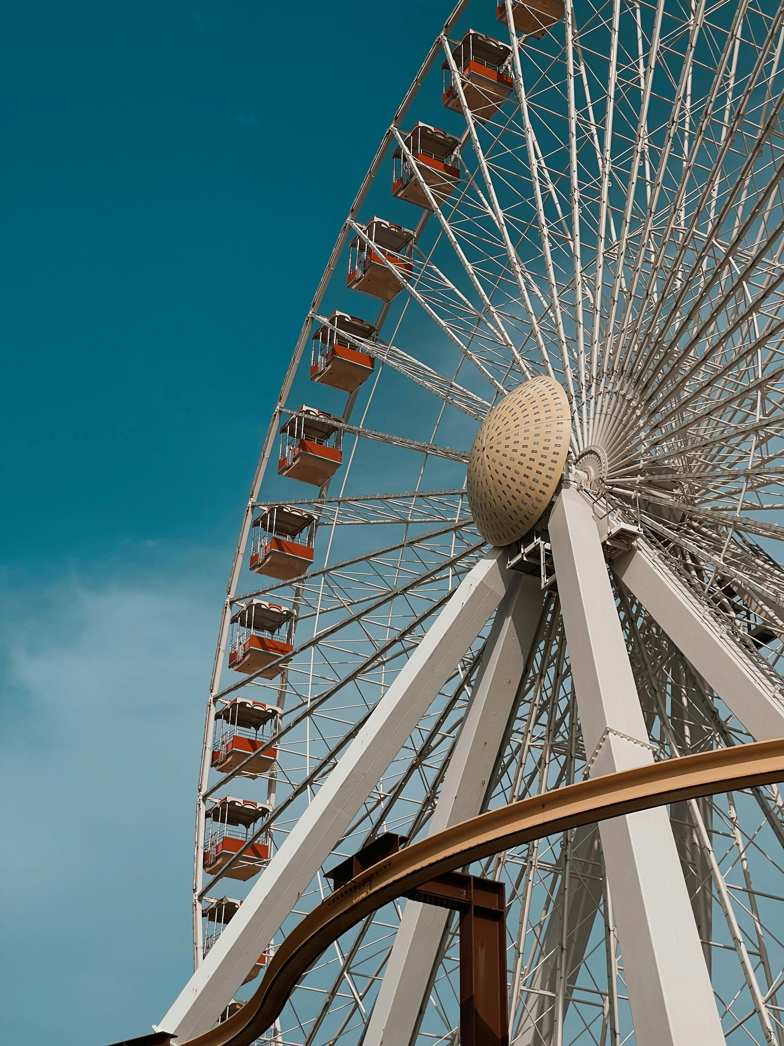 A large Ferris wheel with several enclosed passenger cabins, located against a clear blue sky.