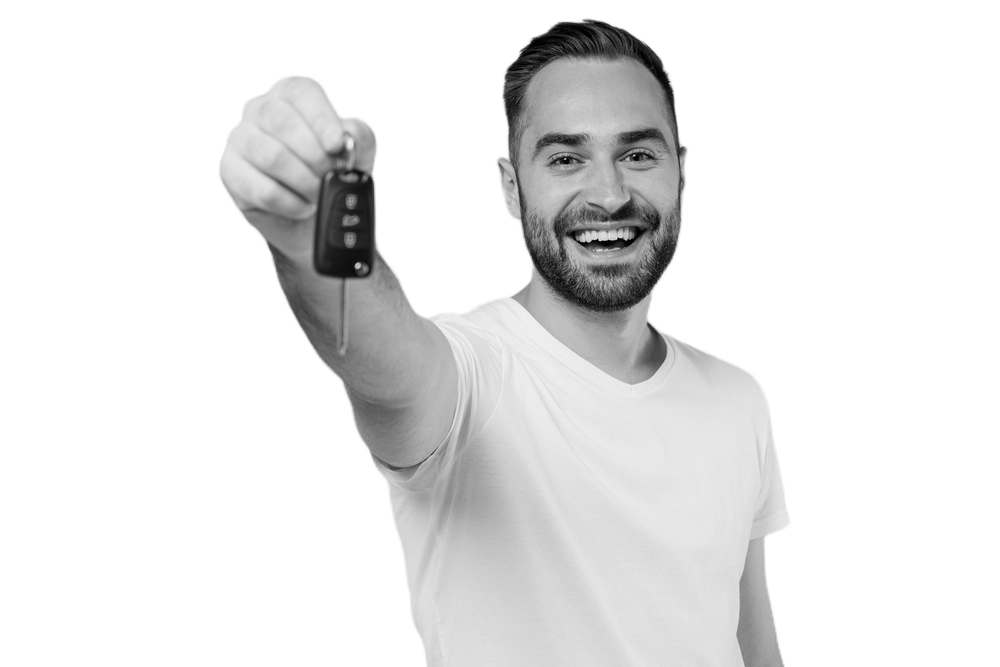 A smiling man holding car keys towards the camera, wearing a white t-shirt.