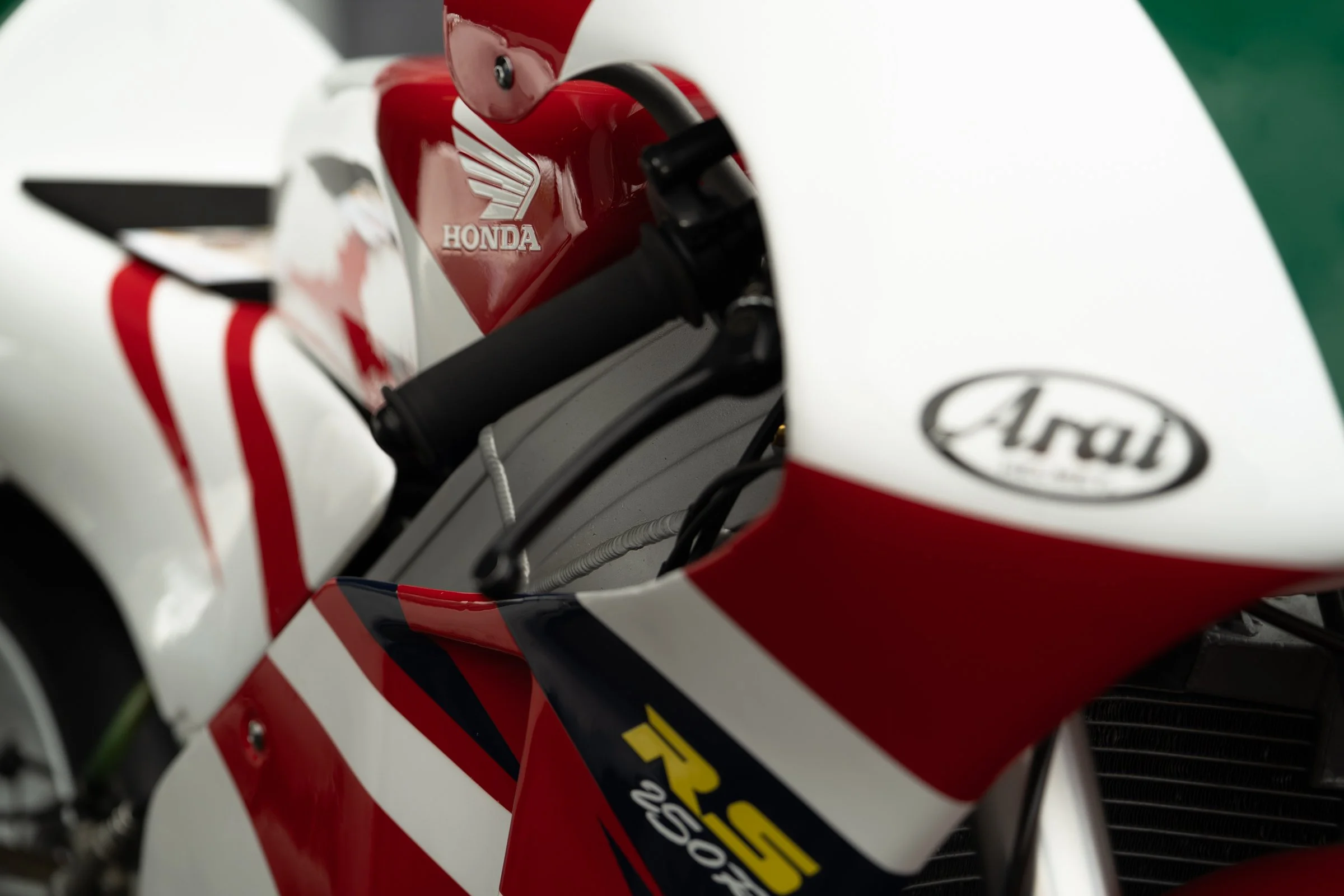 Close‑up of a Honda racing motorcycle with red, white and blue graphics showing the handlebars and Honda logo