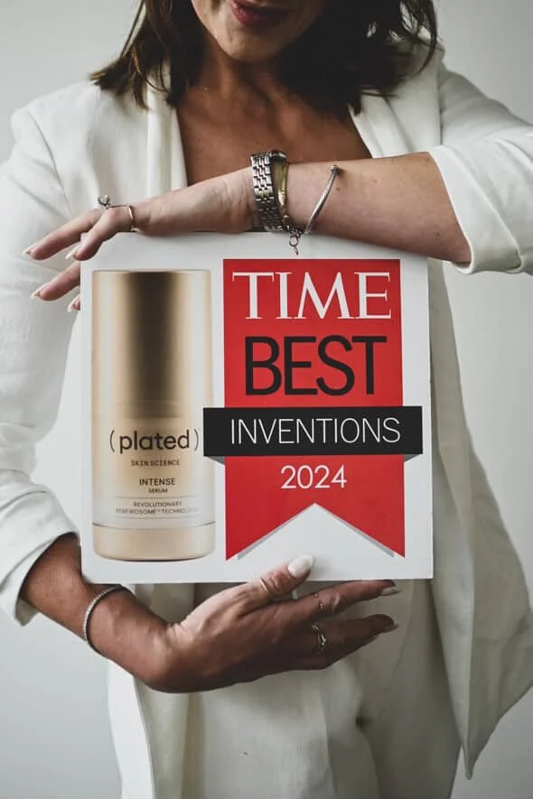 Woman holding a 'Time Best Inventions 2024' award plaque featuring a cylindrical object labeled '(plated) SkinScience Intense'.