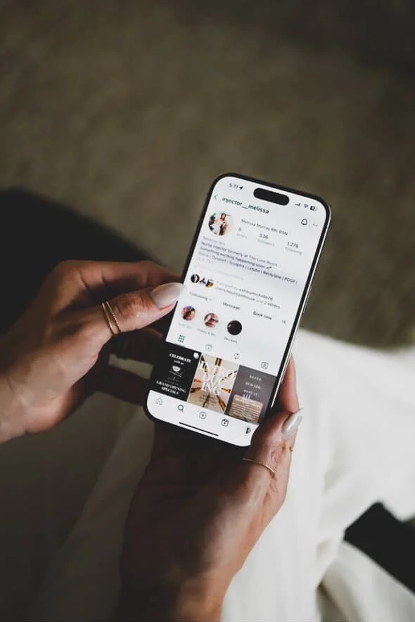 A person holding a smartphone displaying an Instagram profile.