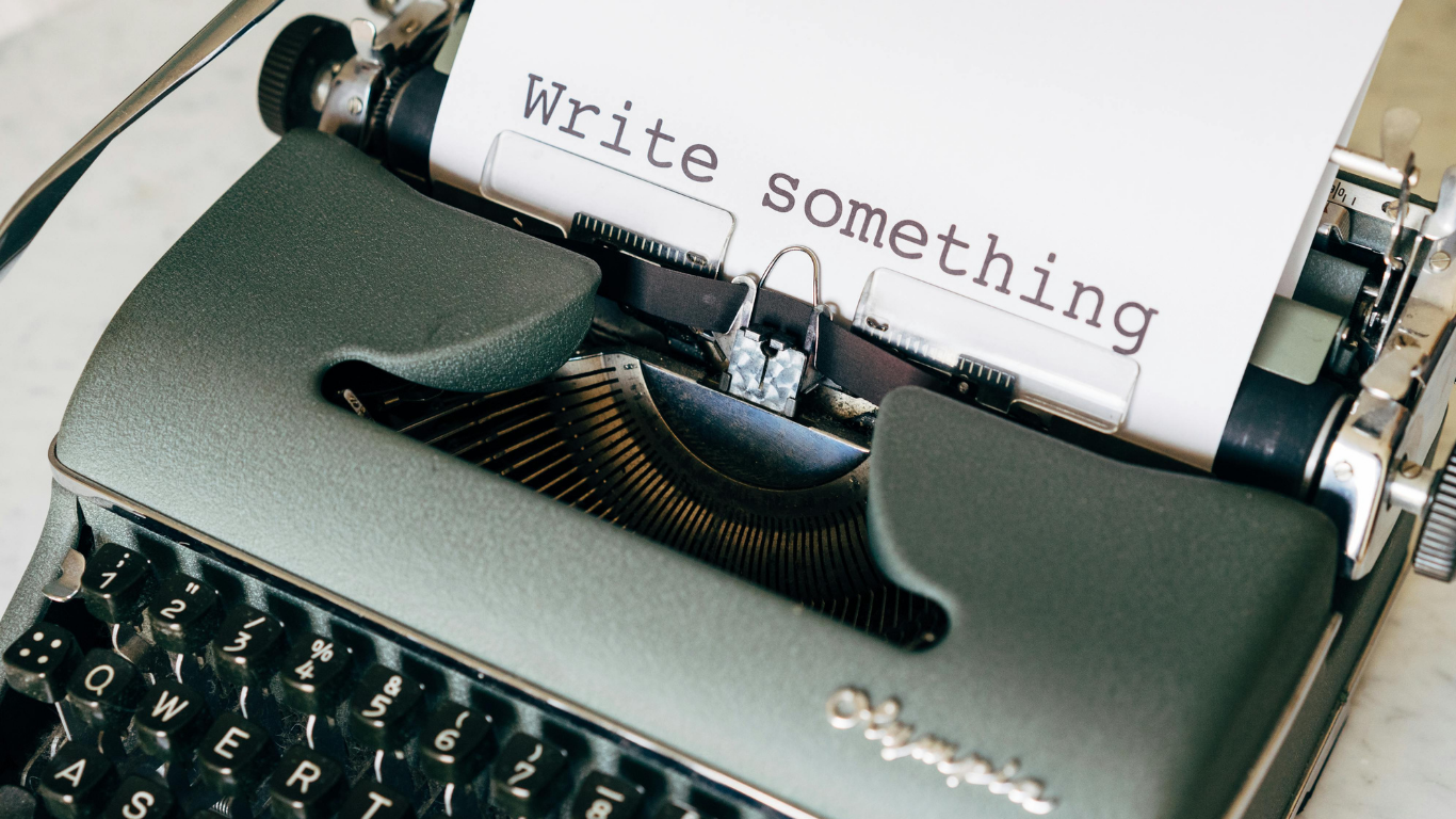 Close-up of a vintage typewriter with a sheet of paper that reads "Write something."