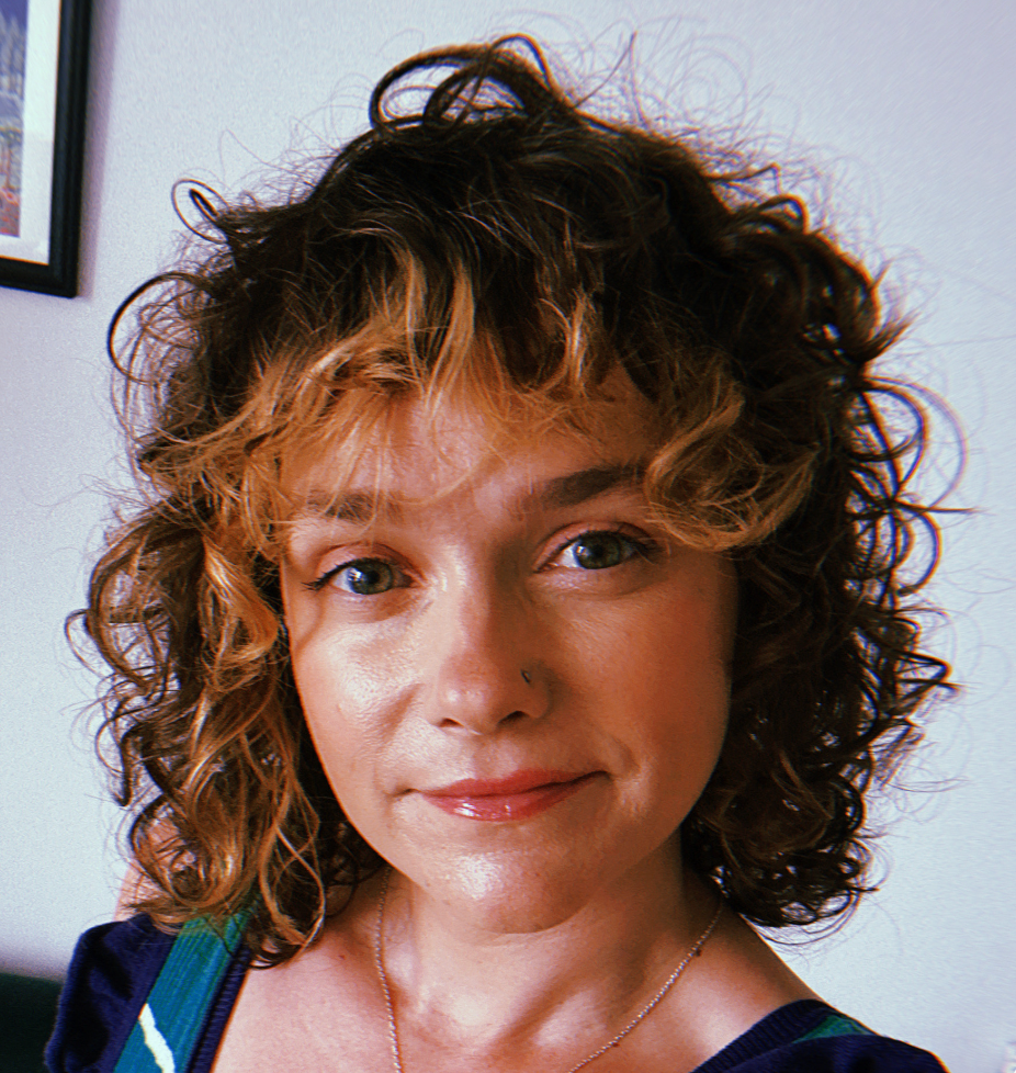 A woman with curly, with two-toned hair, smiling at the camera.