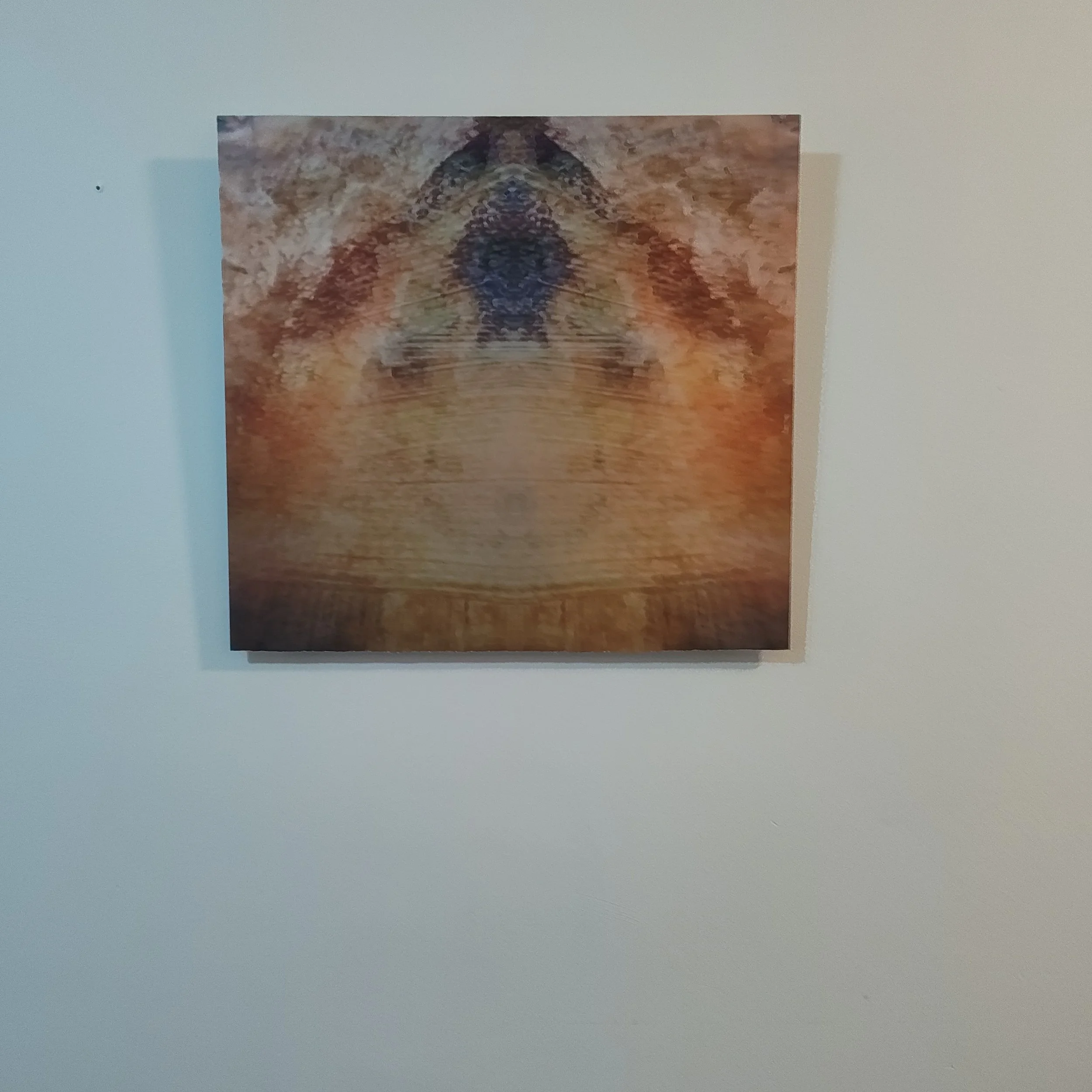 A colorful abstract painting with symmetrical patterns, featuring warm tones like orange, yellow, and red, with some darker and lighter accents.
