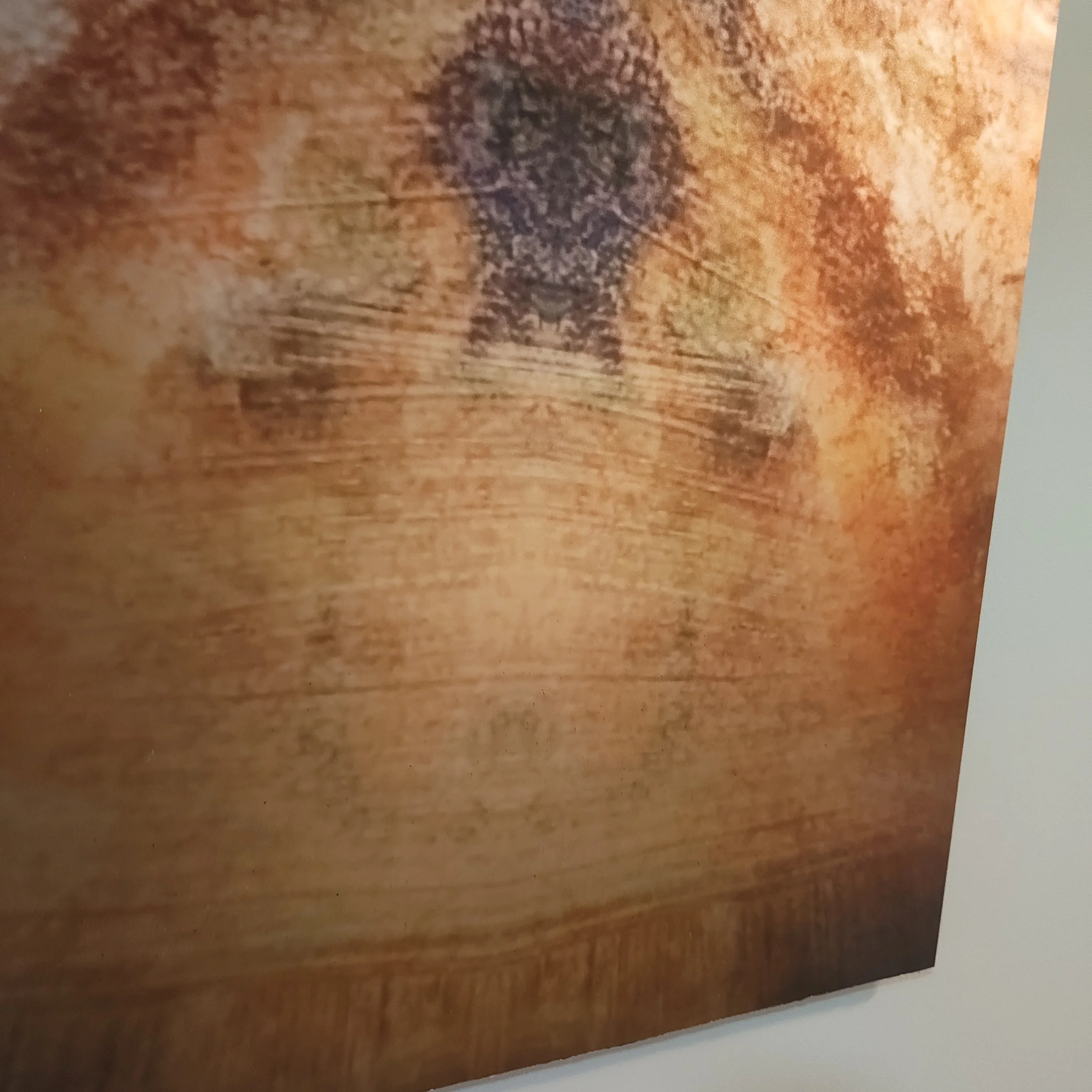 Close-up of a wooden surface with a faded, circular, black stamp or mark.