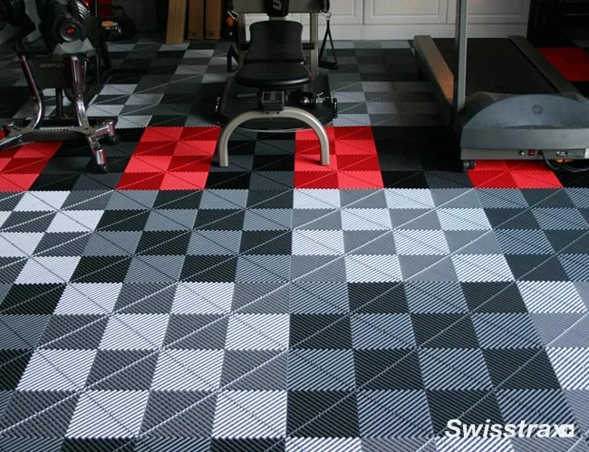 Room with patterned flooring, workout equipment including a stationary bike, weight bench, and treadmill.