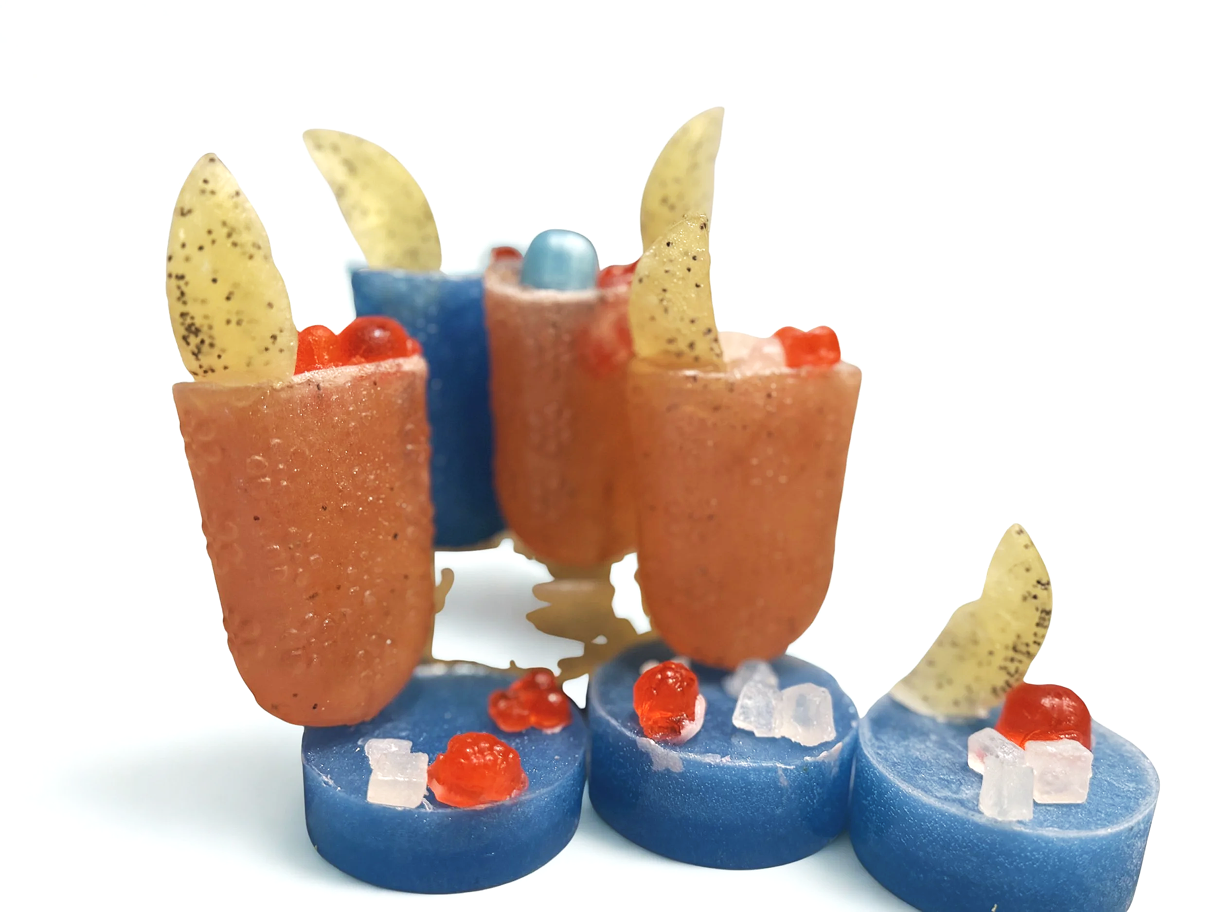 A decorated birthday cake featuring orange cookie-like structures with yellow triangular cookie decorations, a blue sphere in the center, red and sugar crystal toppings, and blue bases with a textured surface.