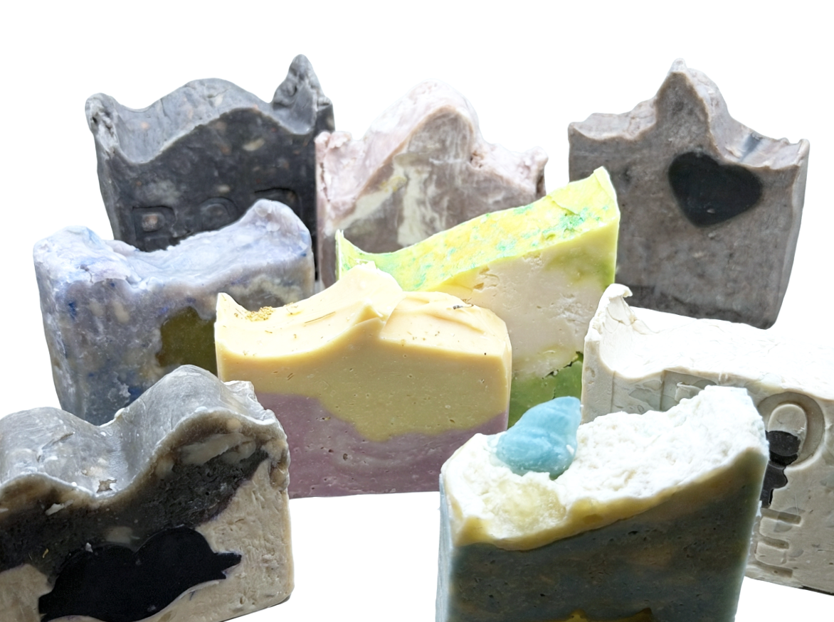 Collection of handmade soap bars with various colors and patterns arranged in a semi-circle. Bode Bars Mini soaps, a collection of 1/2 sized soaps, good for samples or bundling.