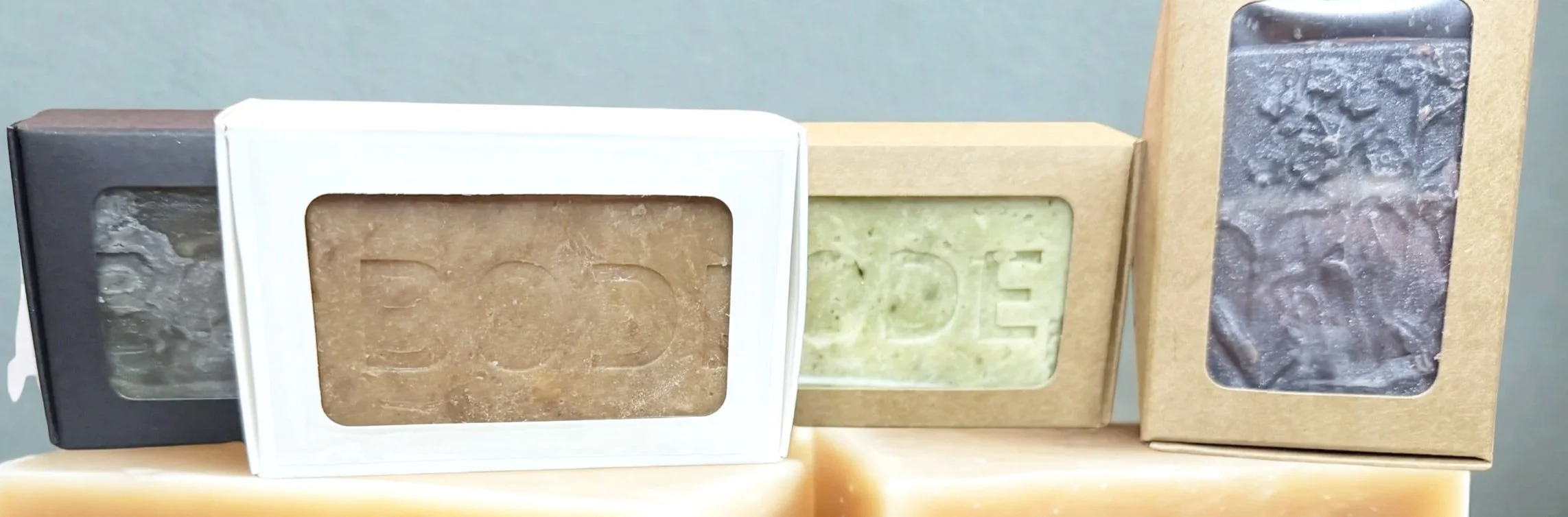 Four bars of soap in boxes with clear windows, each labeled with the word 'SOAP', arranged in a row.