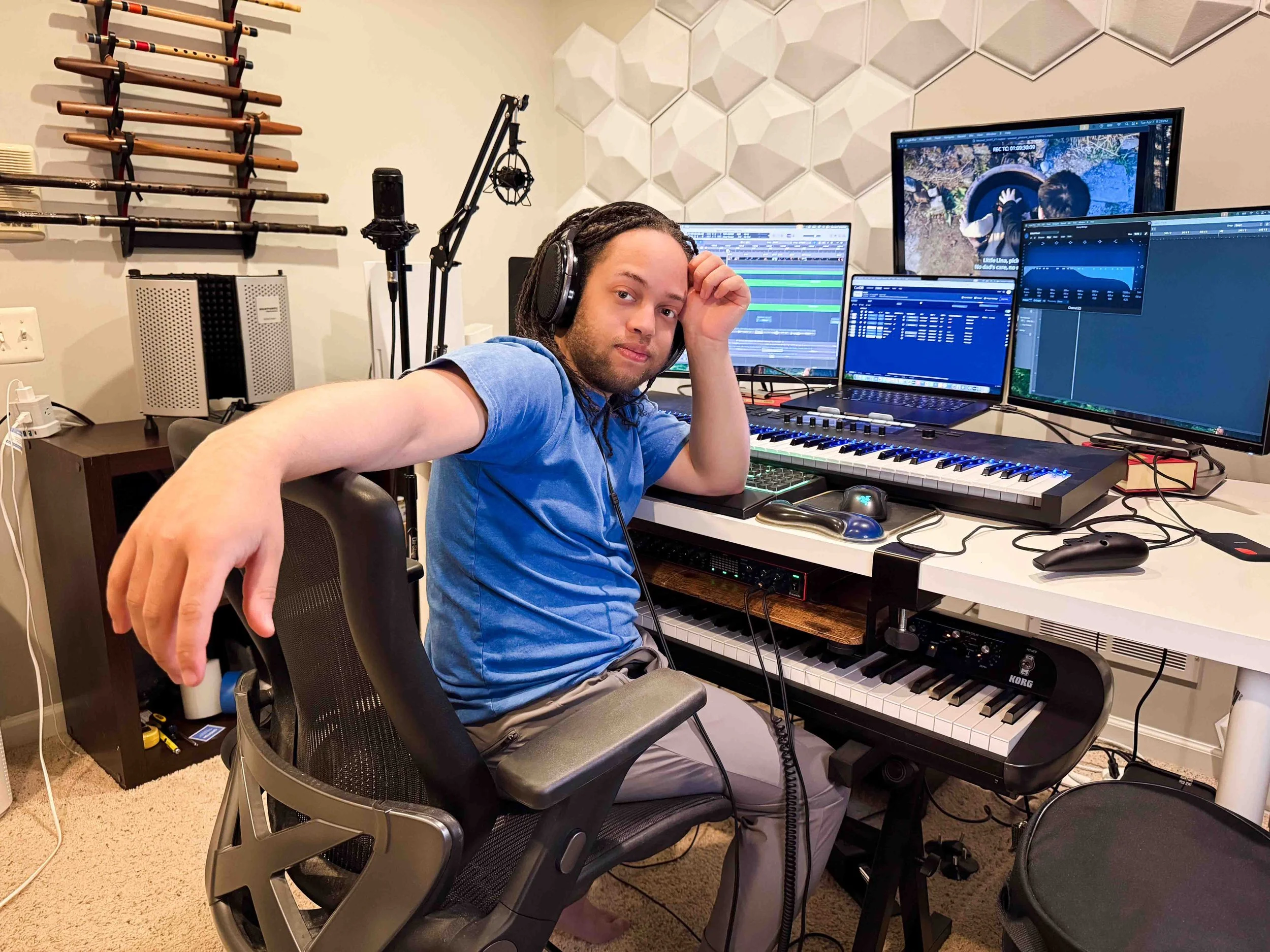 Film and game composer working in a home studio with MIDI keyboard, multiple monitors, and audio production software