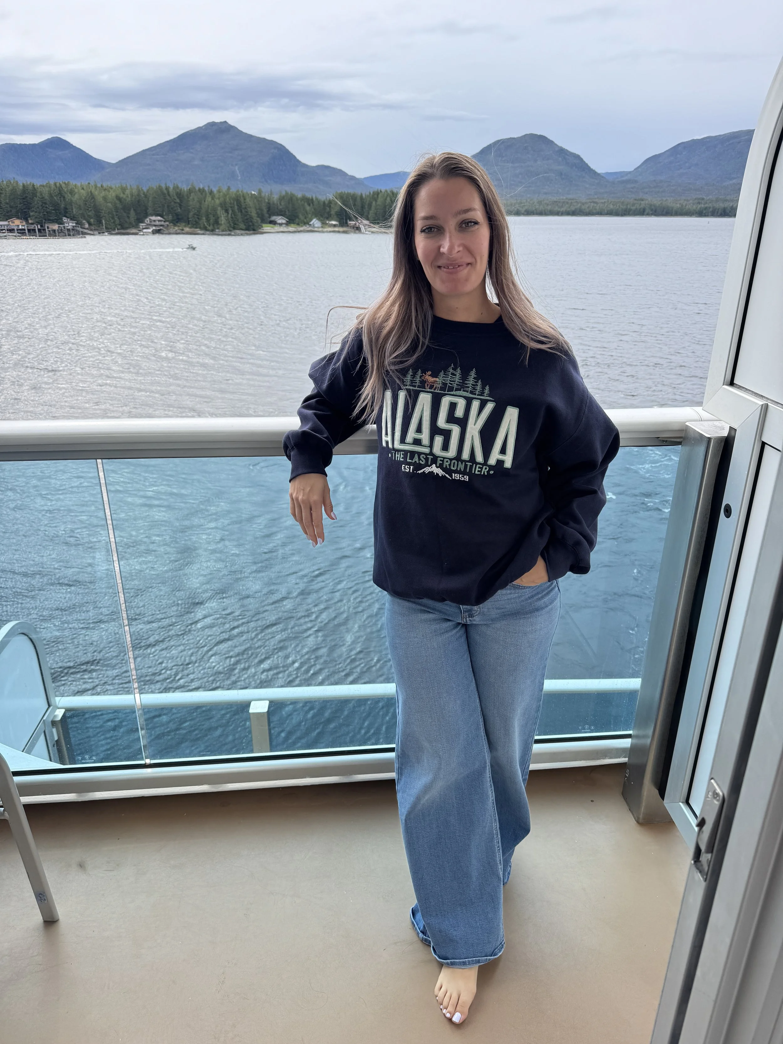Woman standing on the balcony of a cruise ship with alaska in the background