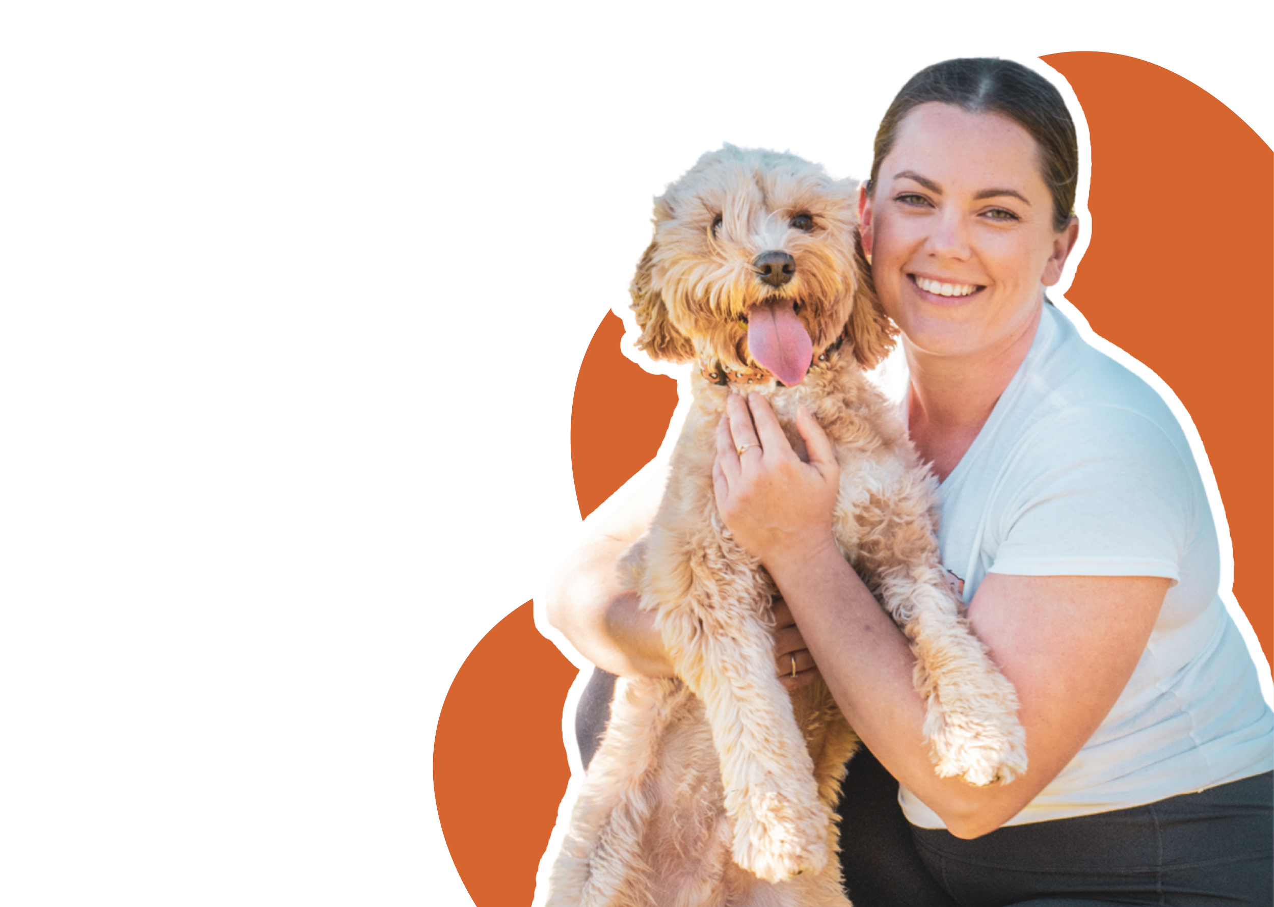 A woman holding a fluffy, tan-colored dog with a happy expression and tongue out, outdoors with a sunlit background.