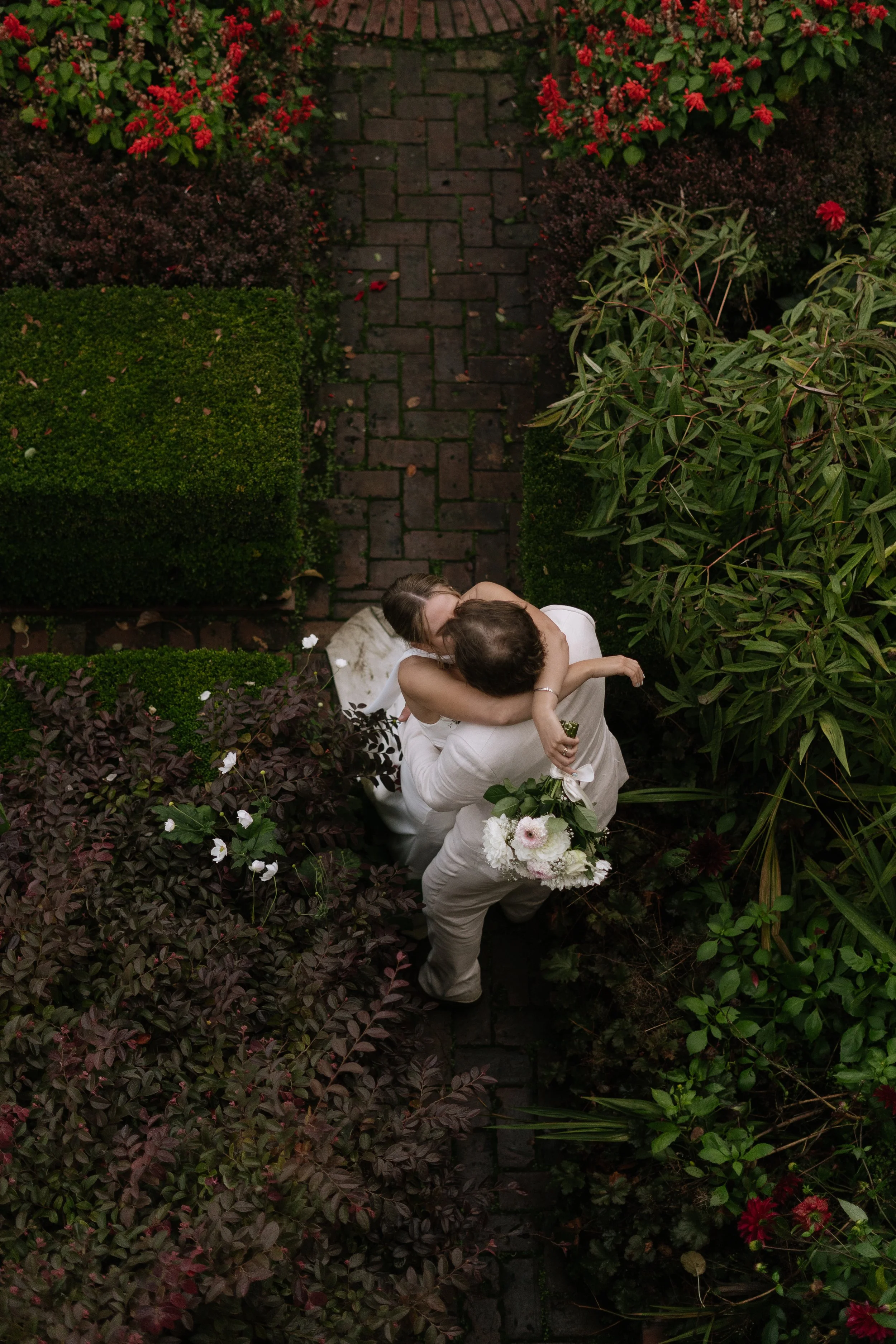 Wedding couple embracing in a kiss within a garden