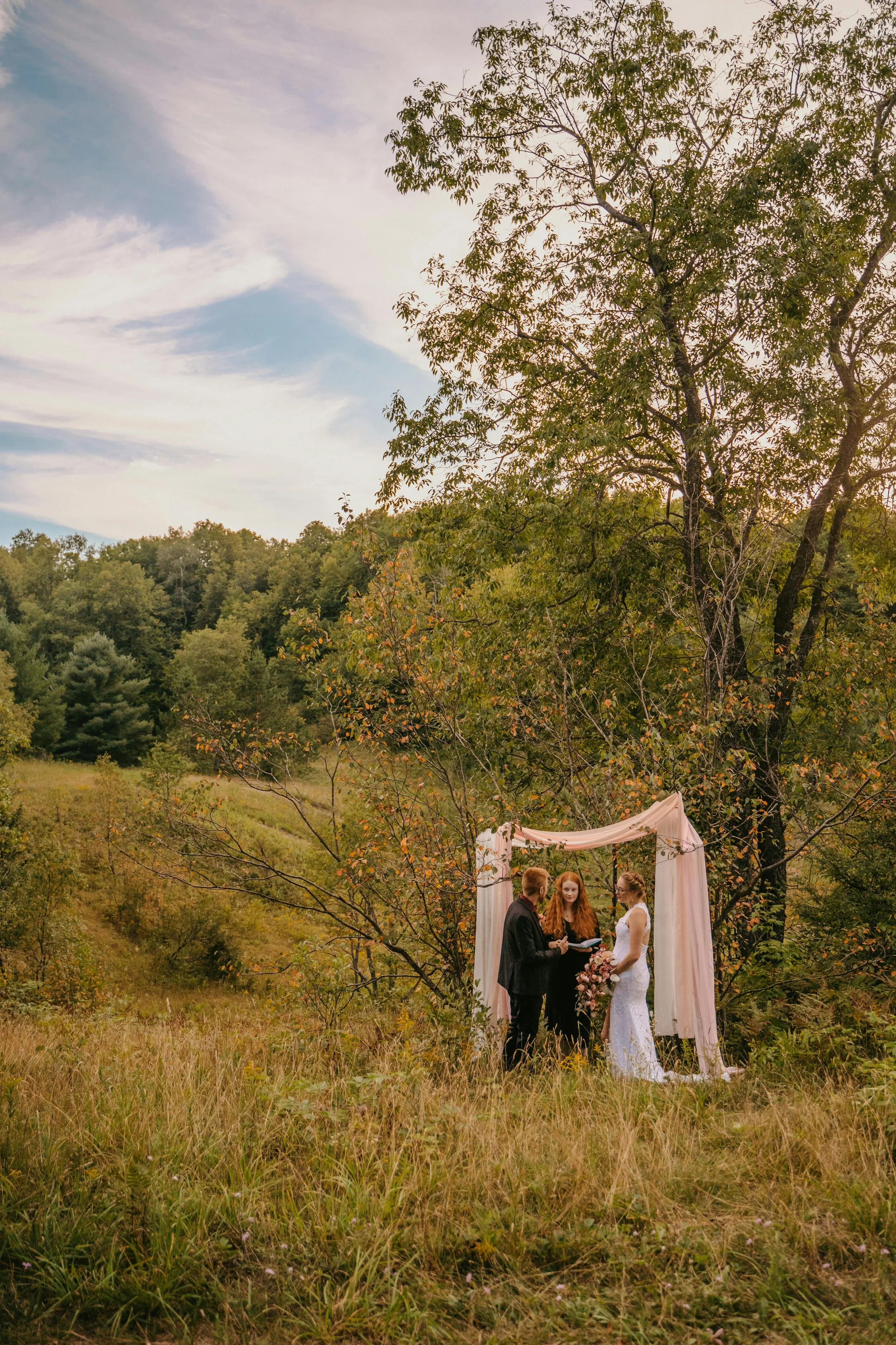 Bride and groom getting married in a field with a celebrant
